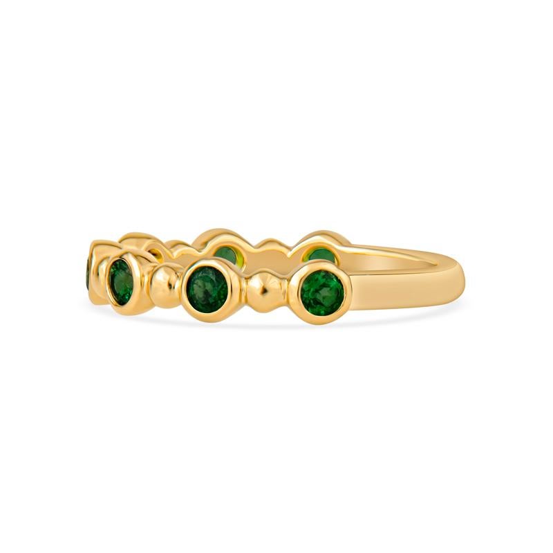 Questo elegante anello in oro giallo 18 carati presenta una deliziosa composizione di gemme di tsavorite naturale di un vibrante colore verde alternate a una perla d'oro. Perfetto per essere impilato o indossato da solo, aggiunge un tocco di