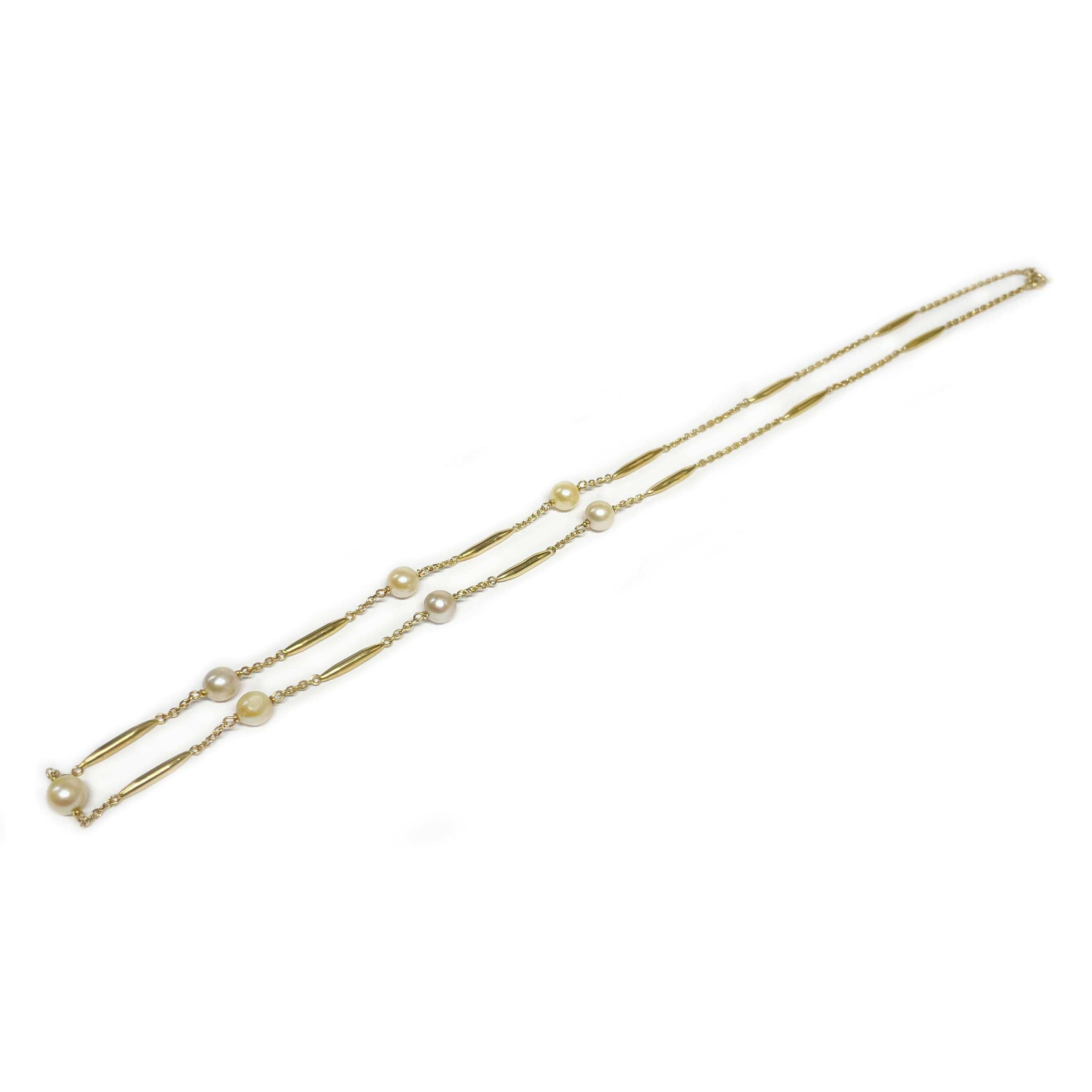 14 Karat Yellow Gold Tubular Pearl Necklace. The necklace features seven 5mm pearls with chain links and twelve gold tubular beads. The pearls vary in color, and one pearl in particular shows wear in a specific area. Stamped on the clasp is 14K. The