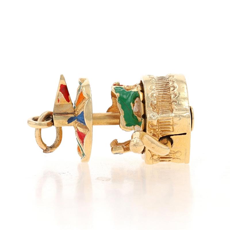 Era: Vintage

Metal Content: 14k Yellow Gold

Material Information
Enamel
Color: Red, Orange, Blue, & Green

Theme: Carousel, Carnival Amusement Fair Ride
Features: When the side handle is turned, the carousel rotates.

Measurements
Tall (from