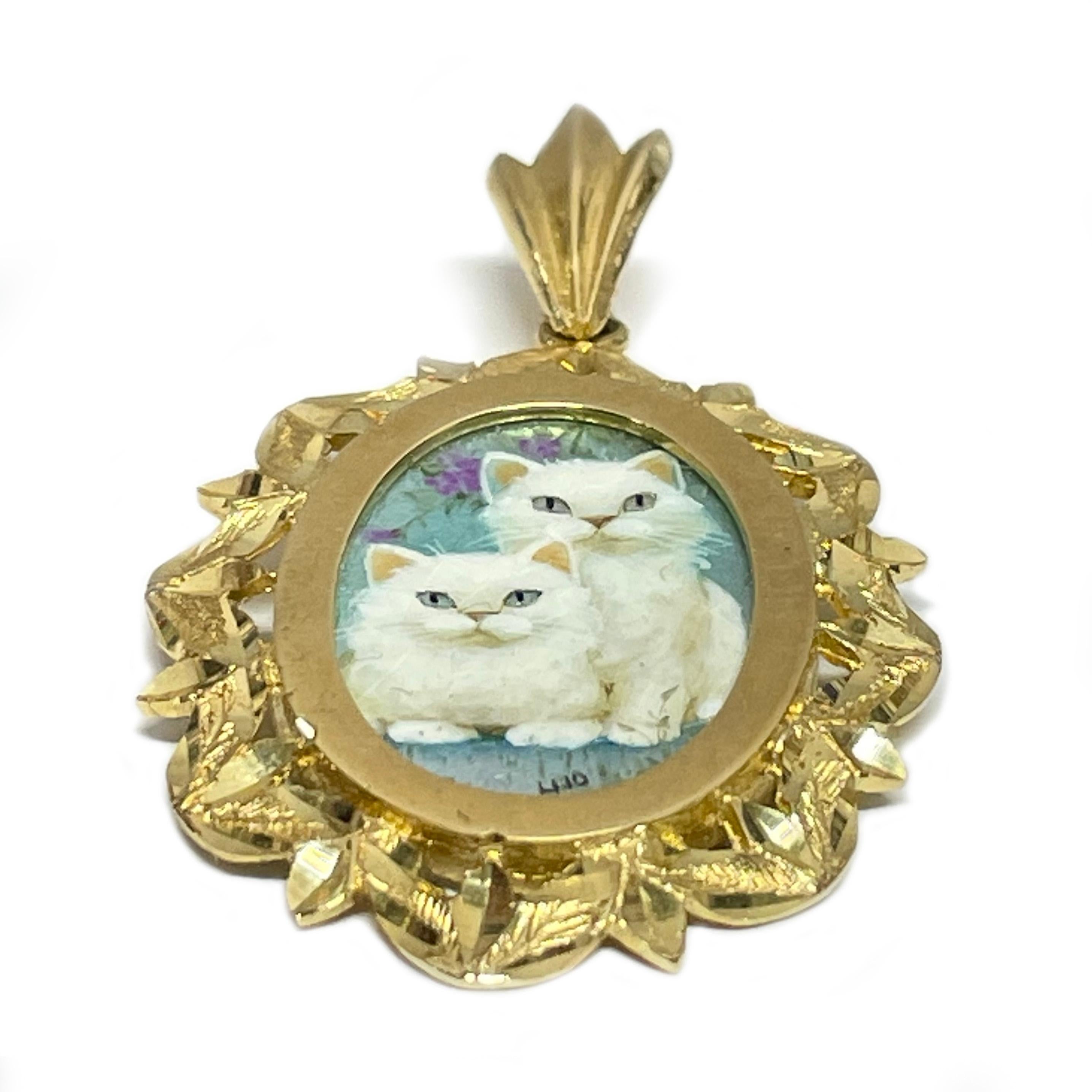 14 Karat Yellow Gold Two White Cats Hand Painted on a Mother of Pearl Pendant. The miniature painting is set in a 14 karat gold ornate oval frame with diamond-cut details. The painting is signed by the master artist, Luo-Afi-Ping and includes a