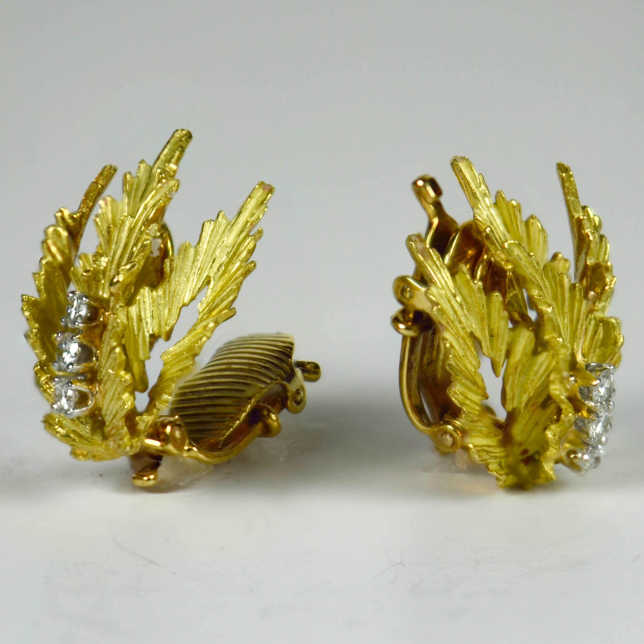 A pair of 18 karat gold clip on earrings designed as a spray of yellow gold leaves,  the central leaf set with a line of three round brilliant cut white diamonds.

Marked 18KT, and patent mark PAT 2423905 for the adjustable tension earclips. Unknown