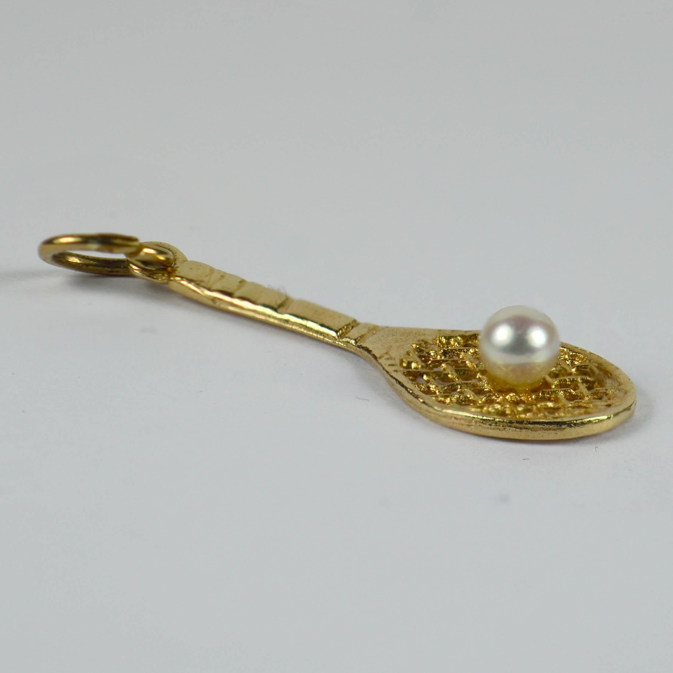 A 14 karat yellow gold charm pendant designed as a tennis racket with a white cultured pearl ball.

Dimensions: 3.5 x 1.1 x 0.6 cm
Weight: 1.29 grams