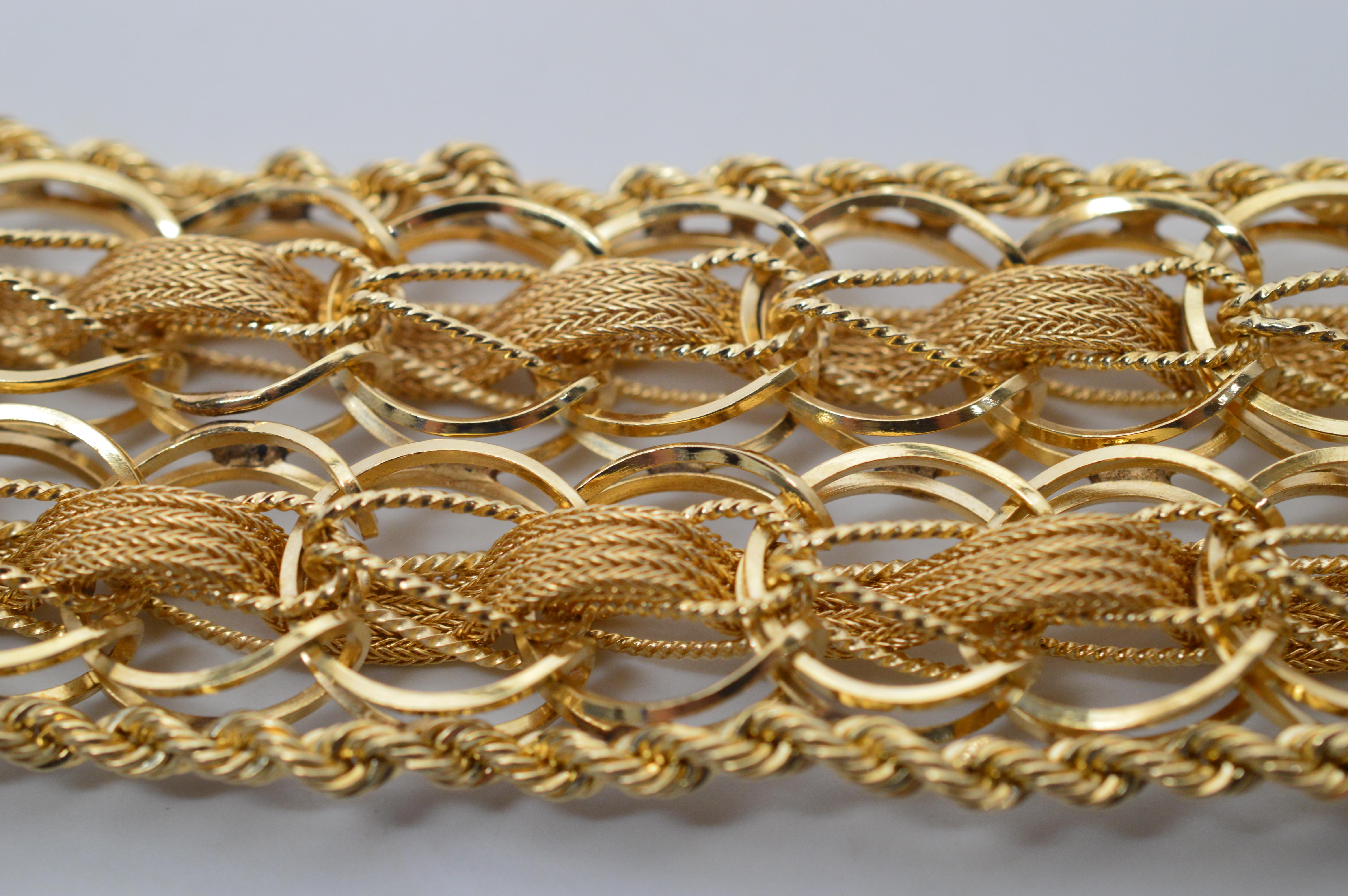 Stunning and beautiful on the wrist are two double rows of bright round fourteen karat 14K yellow gold links are intricately woven with yards of fourteen karat 14K yellow gold wire strands that create this 1-3/8 inch wide flexible bracelet. A