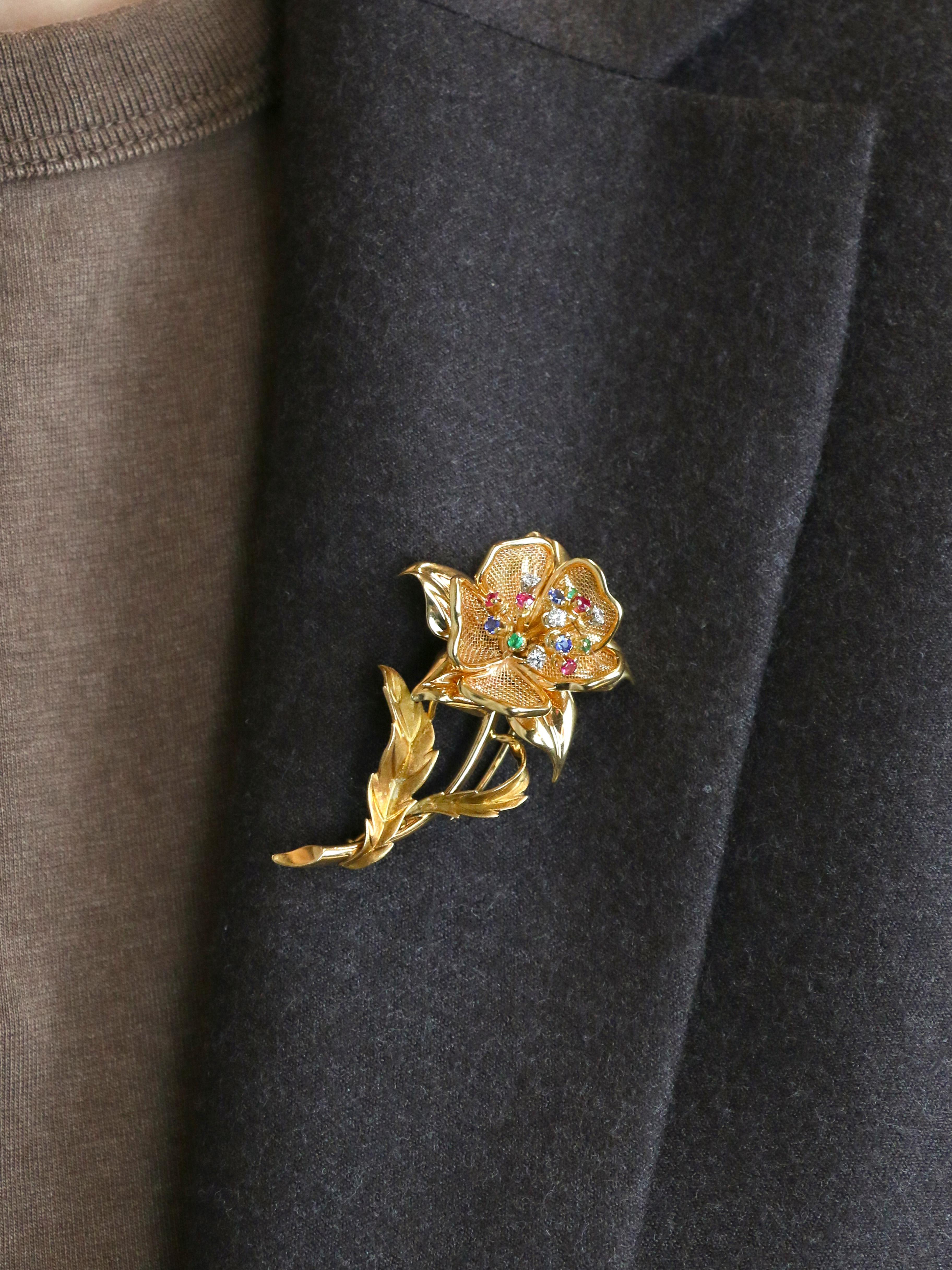 Vintage Yellow Gold Brooch with Precious Stones

18K gold brooch (750°/°°) featuring a flower whose stamens are set with diamonds, emeralds, sapphires, and rubies. The petals are alternately made of solid gold and tulle. The eagle's head hallmark
