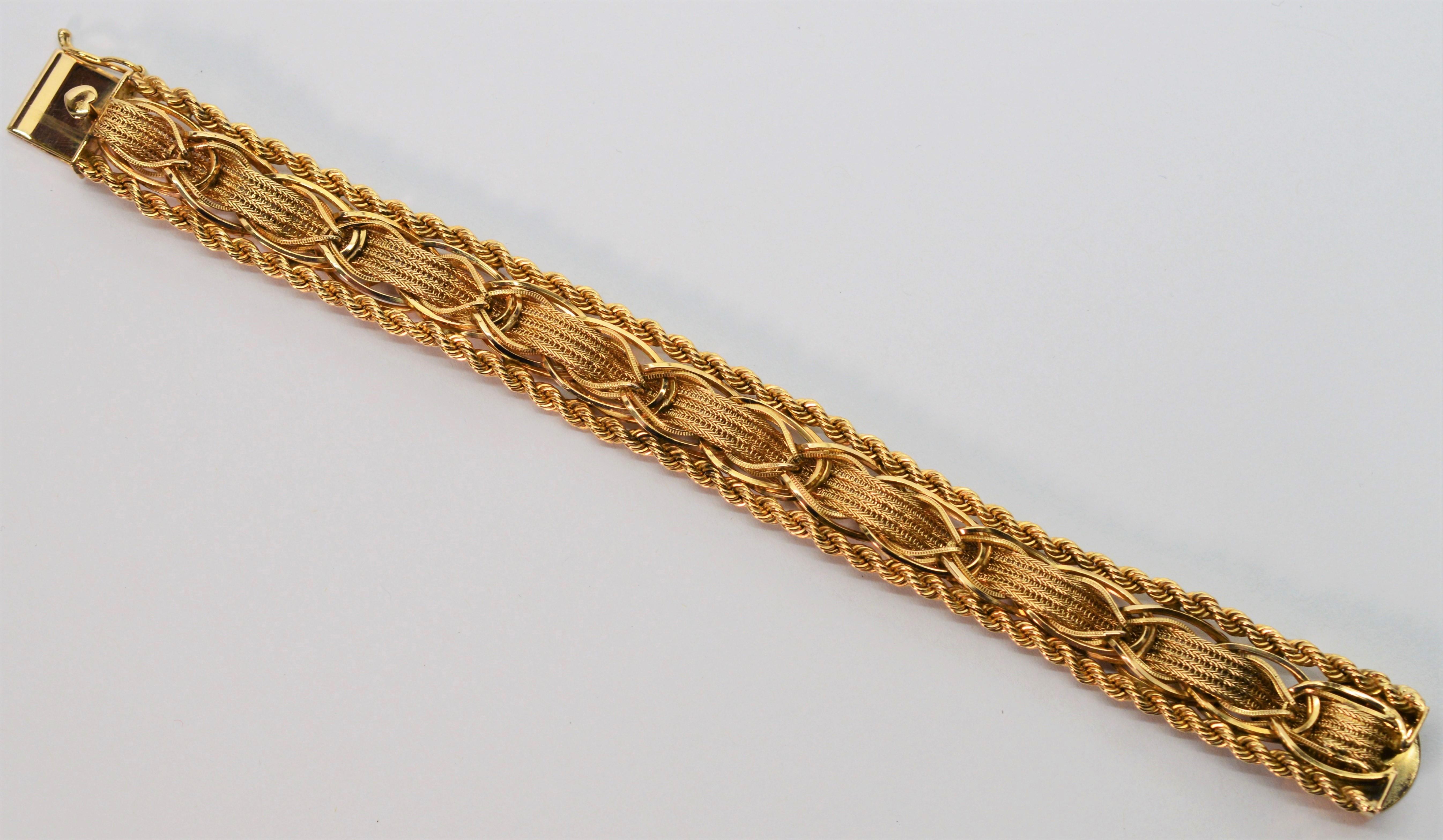 Intricate ribbons of textured fourteen karat 14K yellow gold creatively woven through bright yellow gold links and finished with gold roping detailing make this bracelet an artful find. 
Measuring 7 inches in length and 5/8th inch wide, this piece