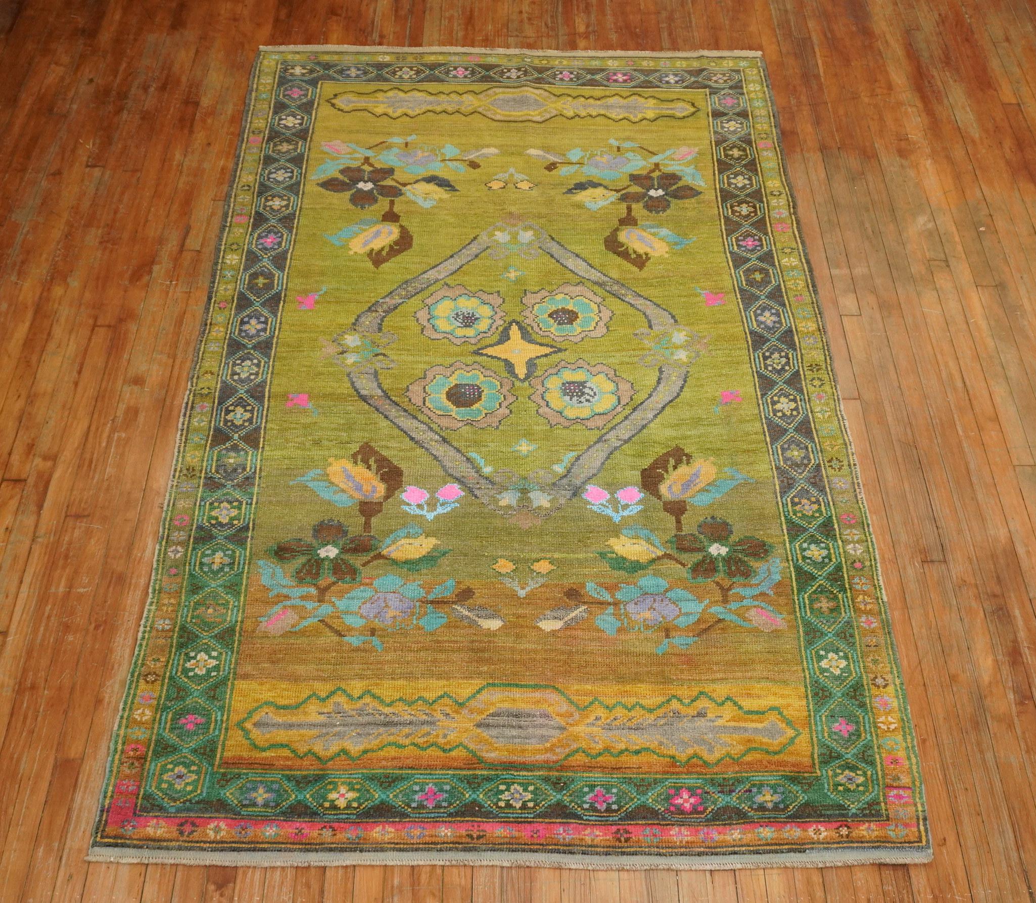 Colorful mid-20th century floral Turkish Anatolian rug. The field is a mossy green color, accents in bright blue, yellow, brown and hot pink,

circa mid-20th century. Measures: 5'7