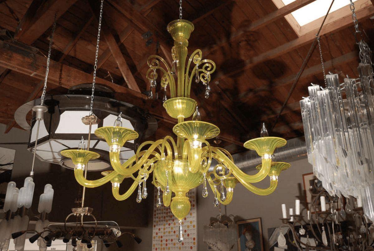 An elegant and colorful yellow green Murano glass chandelier. Has eight arms. Decorated with clear glass dangling drops.