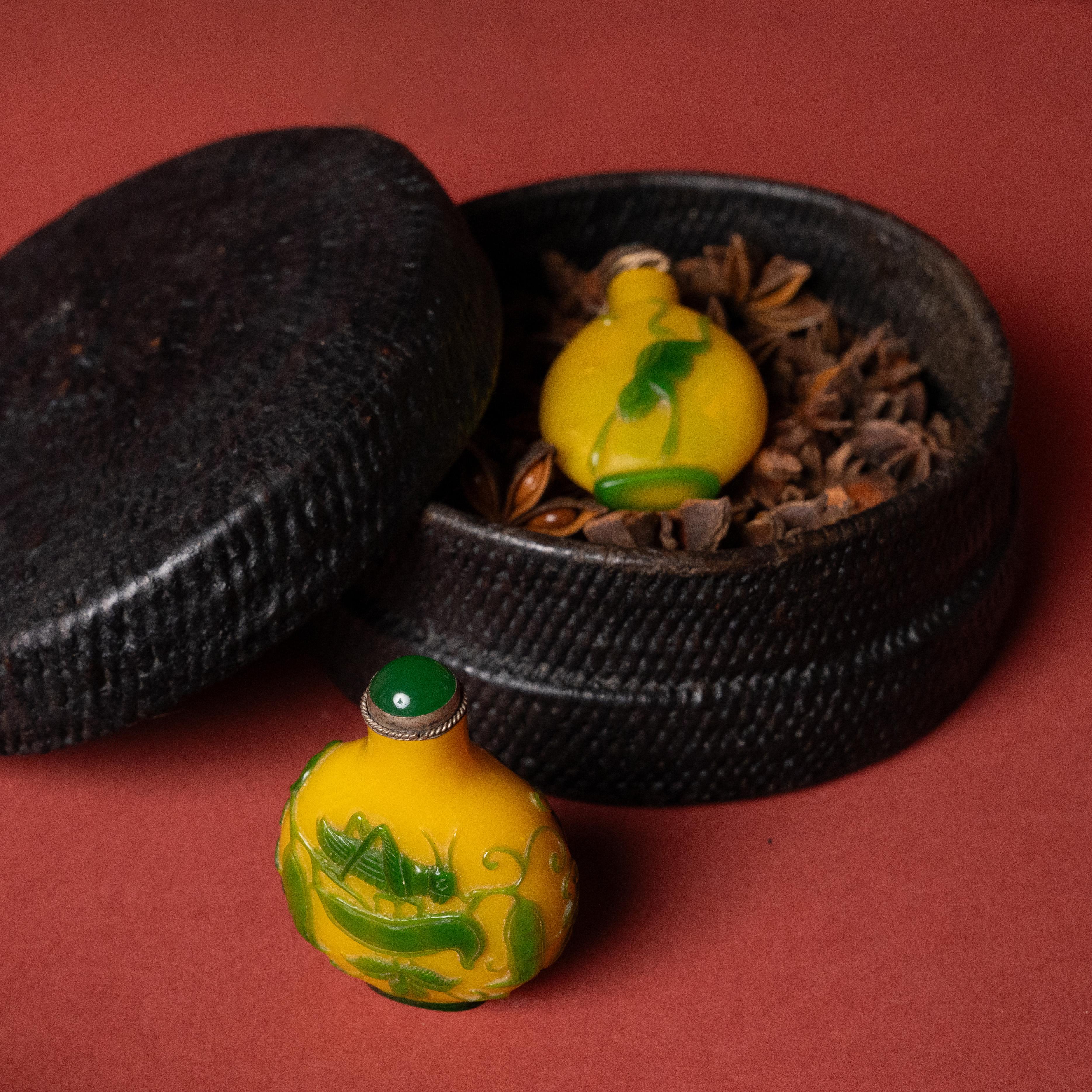 Avec ses couleurs vives et ses sculptures complexes, cette petite bouteille à priser chinoise du début du 20e siècle est un bel exemple de l'art du verre de Pékin. Le petit flacon est sculpté dans une couleur populaire connue sous le nom de 