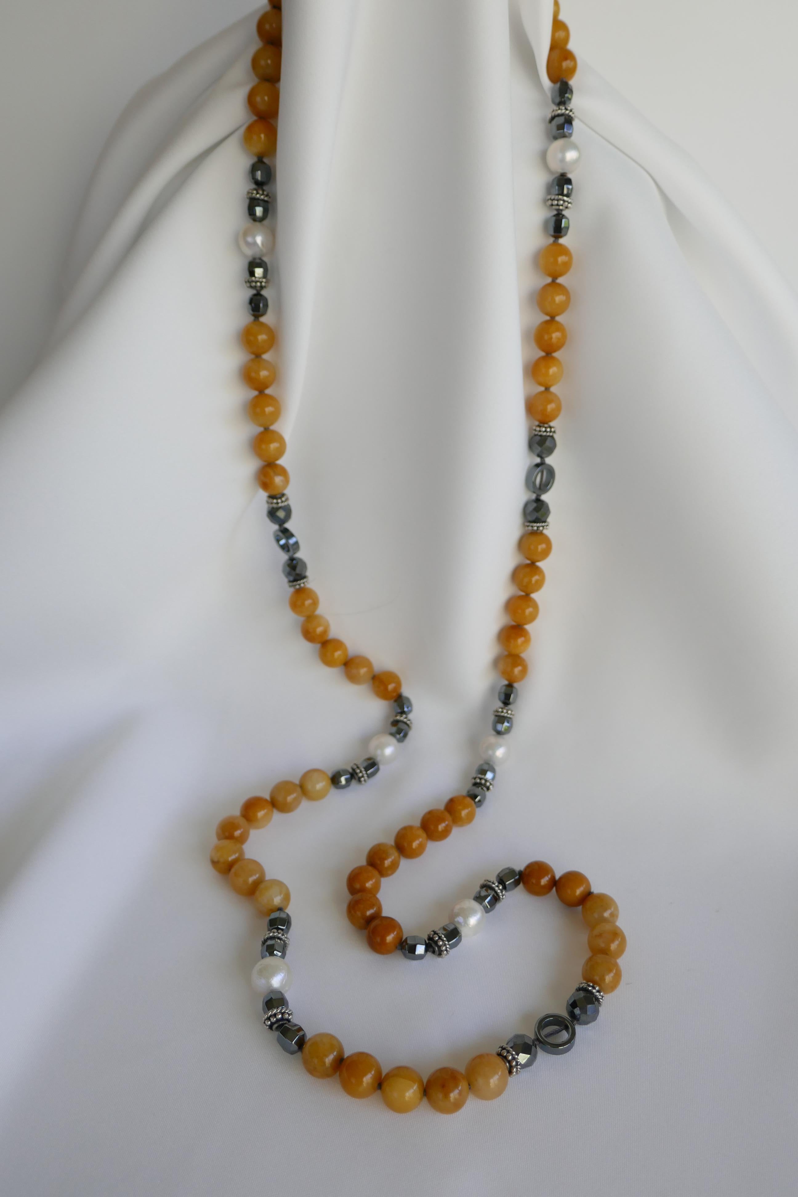 This necklace is made of 10mm yellow jade, faceted hematite, 12.5mm - 13mm white cultured pearls and interspersed with 925 sterling silk cap beads. The necklace is individually knotted on dark grey silk thread which is part of the design with a 925