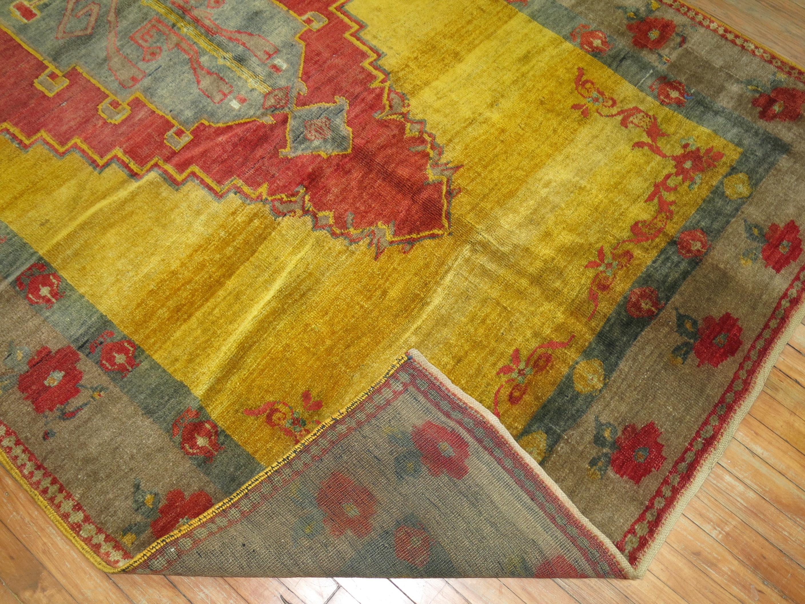 A highly unusual Turkish rug with a large red medallion in soft red on a sunny yellow field with a pretty grayish floral border.

5'9