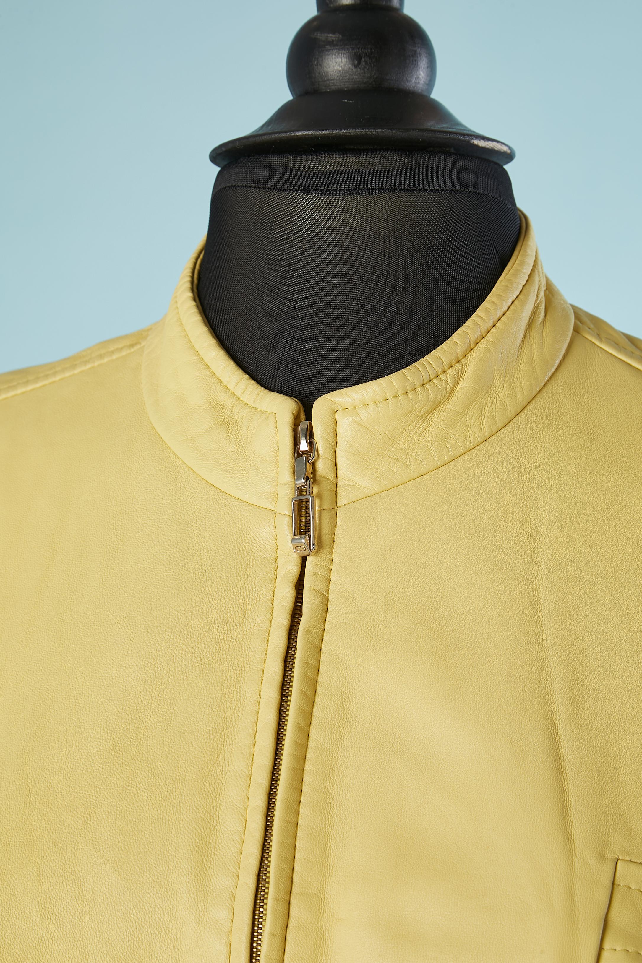Gelbe Lederjacke mit Reißverschluss vorne in der Mitte. Futter aus Rayon mit Markenzeichen. Schulterpads. Brusttaschen mit Reißverschluss. 
GRÖSSE 40