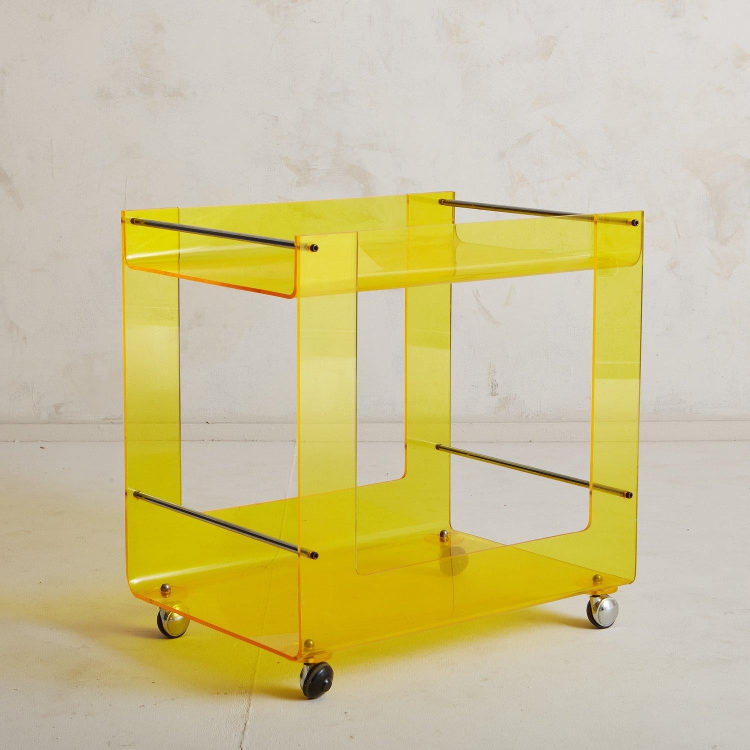 A 1960s yellow lucite bar cart attributed to Rafael Carreras Puigdengolas for Tramo. This sleek trolley bar cart has an angular frame with two tiers perfect for displaying your bottles and barware. It has chrome support bars and stands on four
