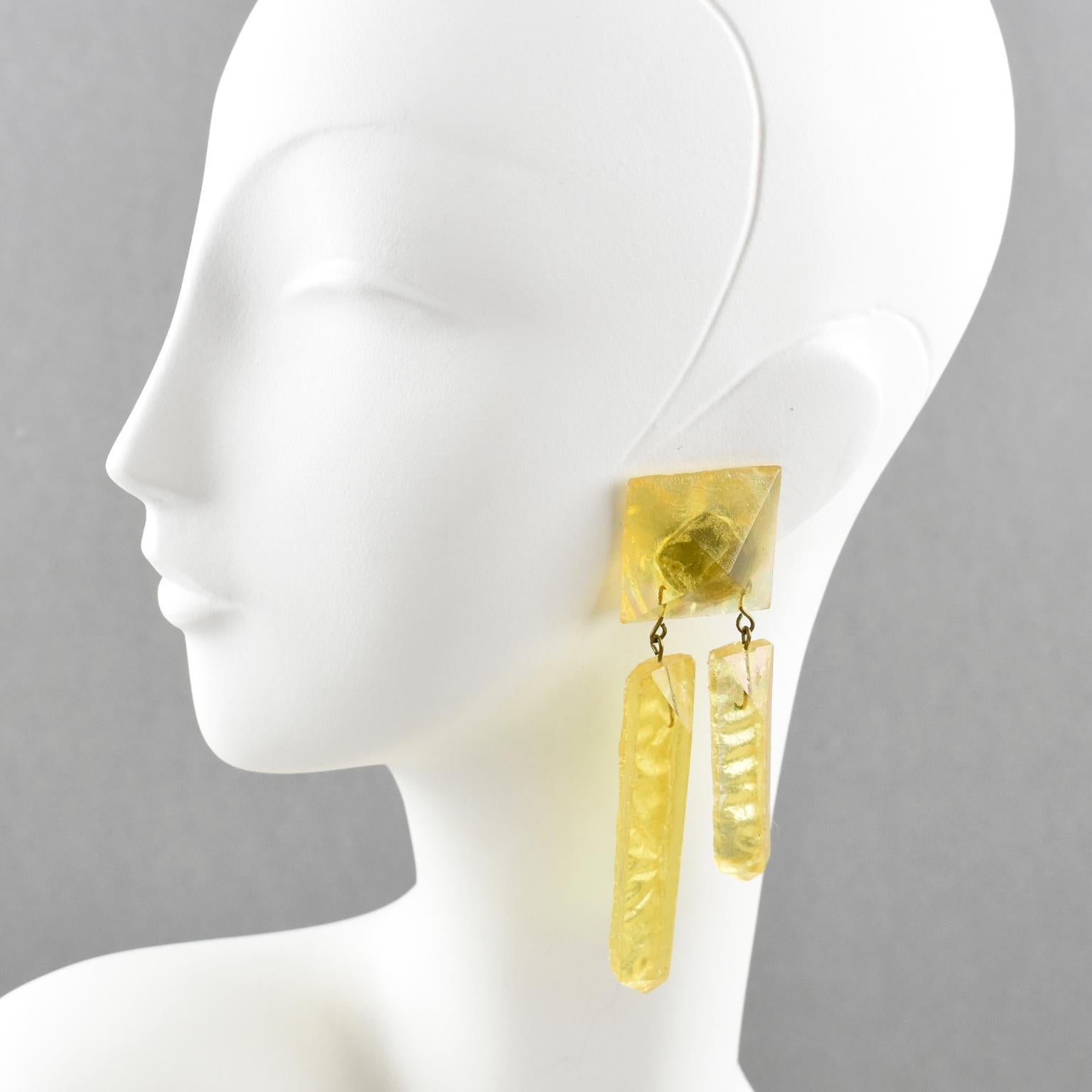 These stunning oversized carved Lucite clip-on earrings feature a dimensional dangling shape with raw textured carved ice cubes in luminous transparent pearlized yellow color. This design is very unusual. There is no visible maker's