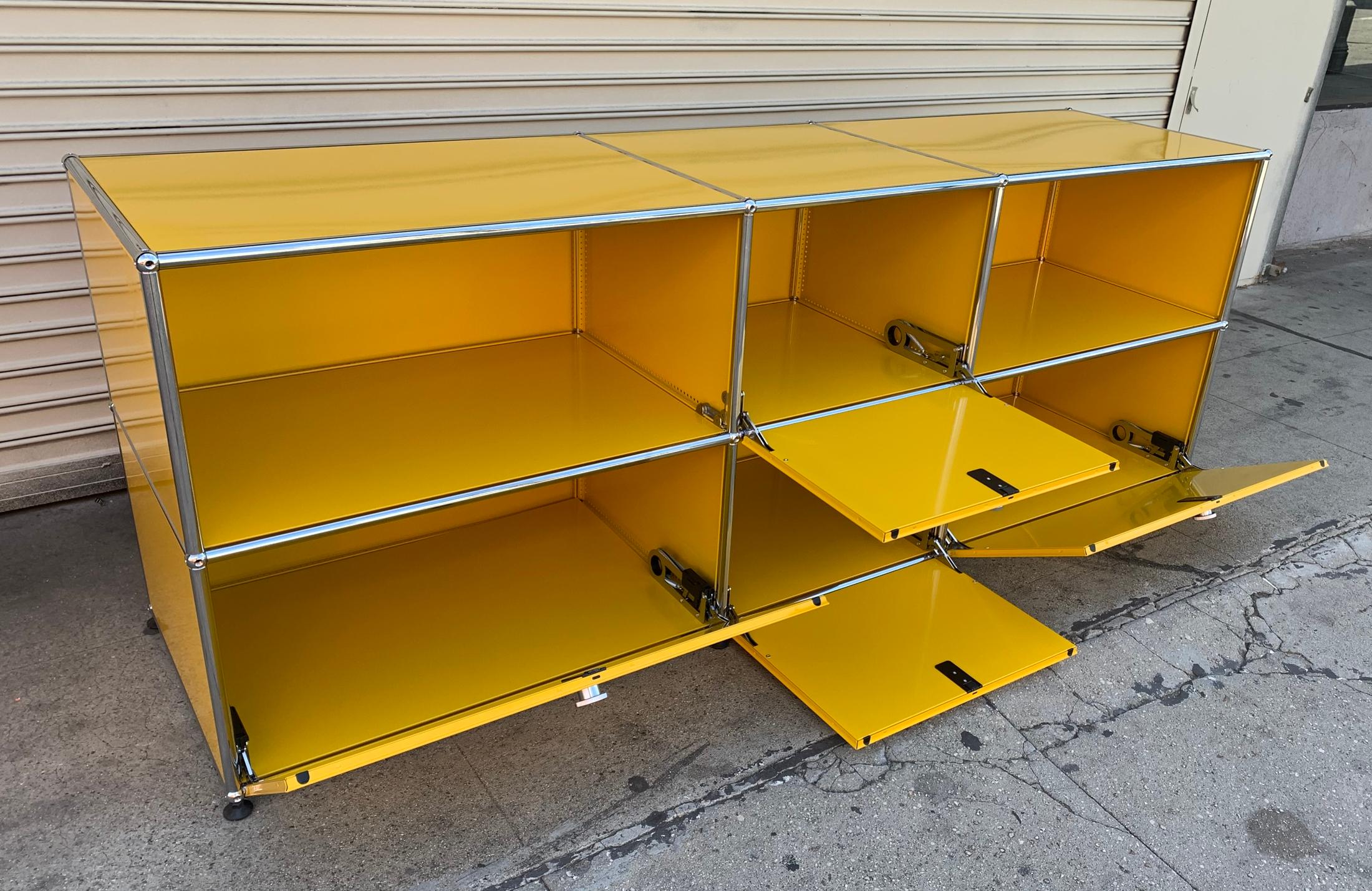 Beautiful metal credenza designed and manufactured in Switzerland by USM Haller,
The piece has 3 lower compartments and 1 upper compartment and two open spaces, the doors swing down to open and it sits in black plastic casters.
The piece is in