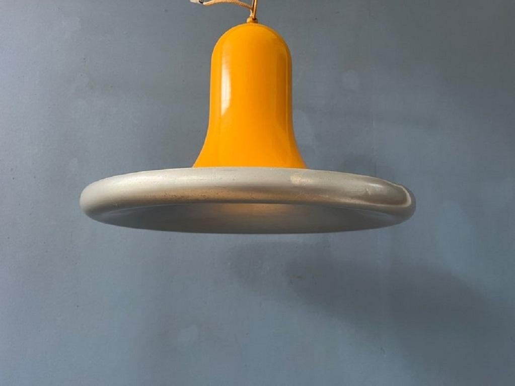 Rara lampada a sospensione gialla della metà del secolo a forma di UFO o di cappello. La lampada è realizzata in metallo e ha una laccatura gialla lucida. Il paralume di questa lampada a sospensione è tipicamente sferico o a forma di piattino, che