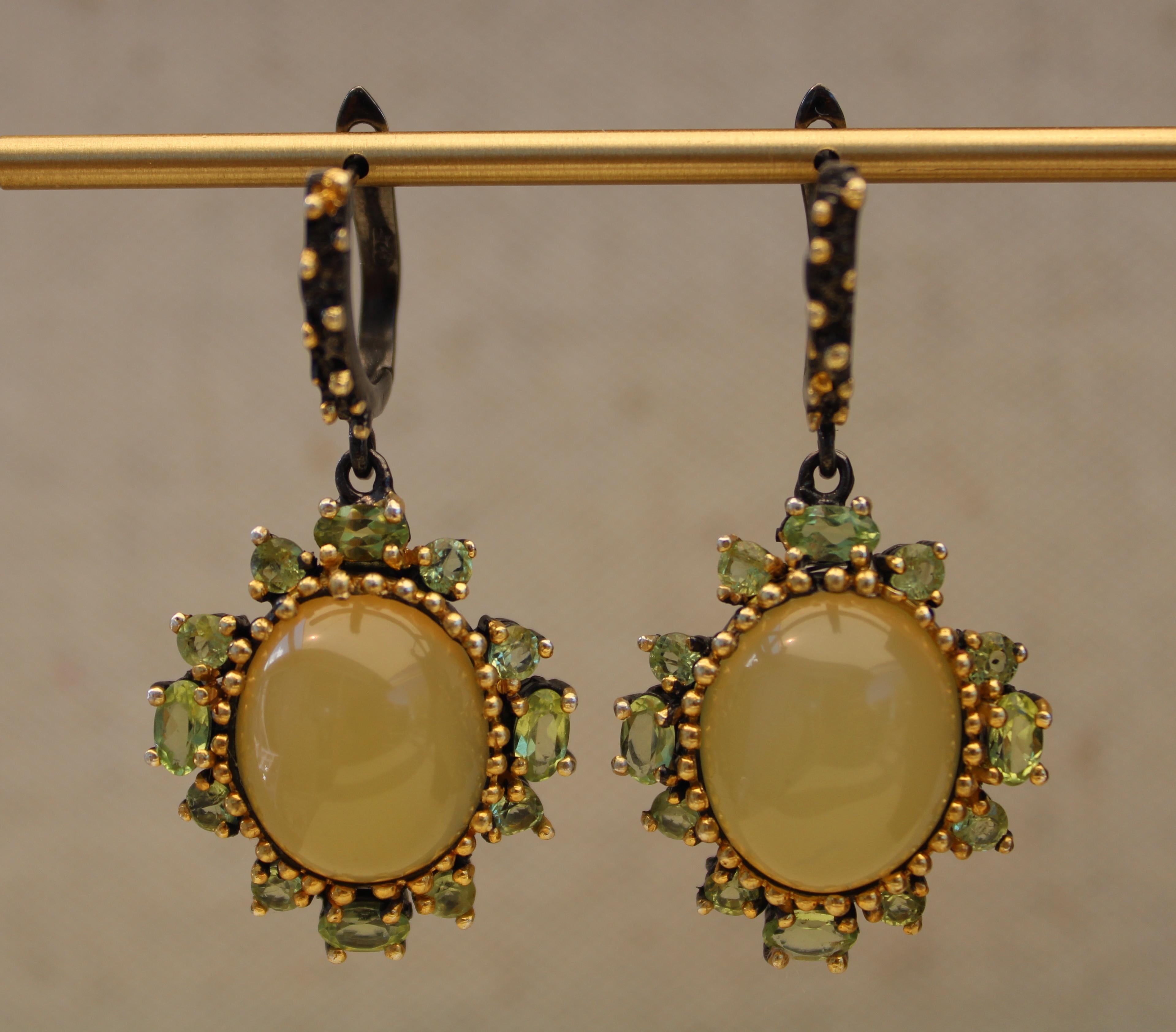 Pair of yellow opal cabochon earrings with oval and round peridot gemstones. These earrings are one of a kind. The gemstones are from Jaipur ethically soured and hand selected. 
They are cast in sterling silver plated in black rhodium and 14k gold.