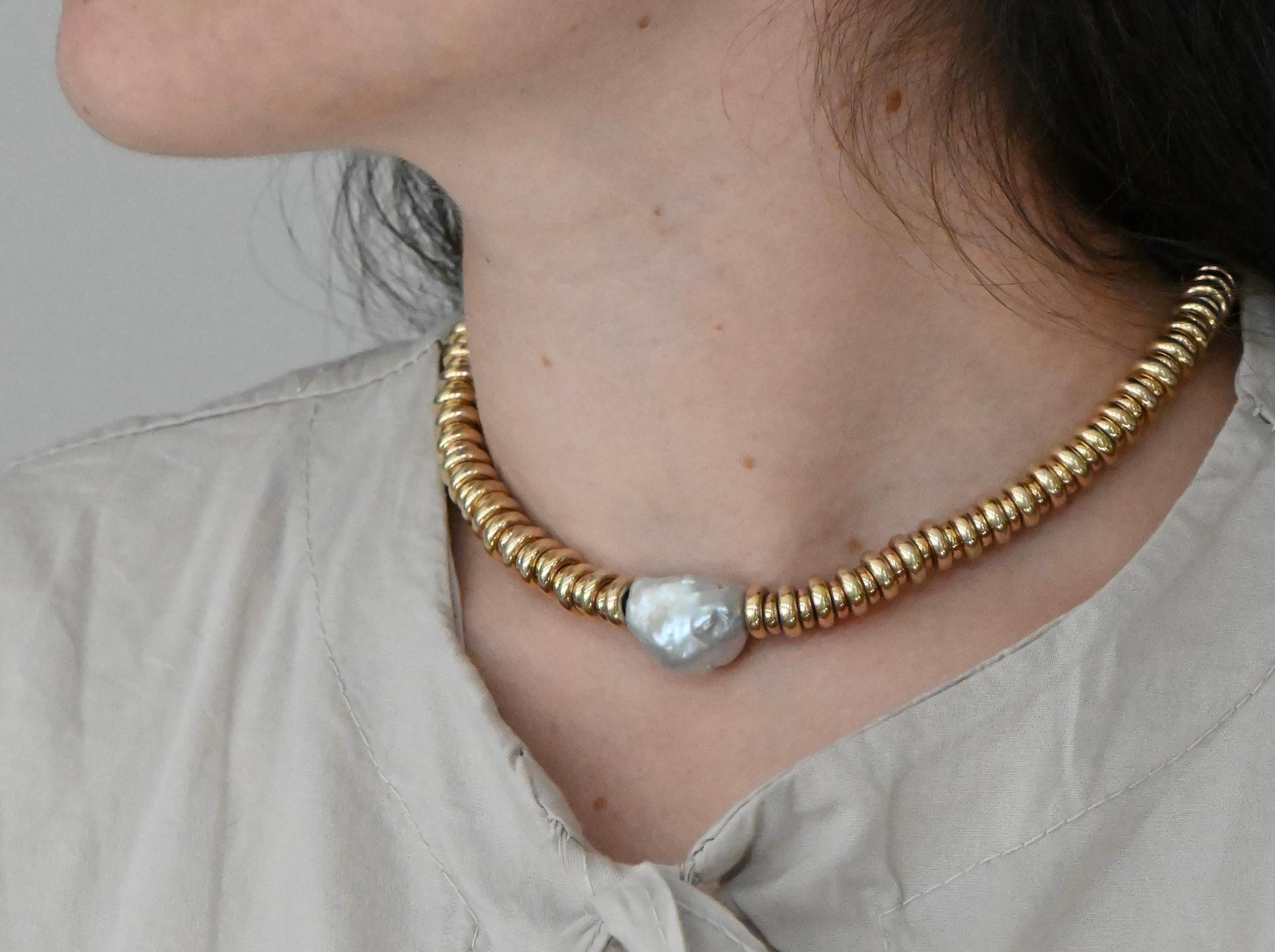 Questa collana in argento e oro giallo, montata su un filo rivestito, è un pezzo elegante e senza tempo. Al centro, una perla grezza perlata illumina la collana e valorizza il tuo viso con la sua naturale luminosità. La chiusura regolabile sul