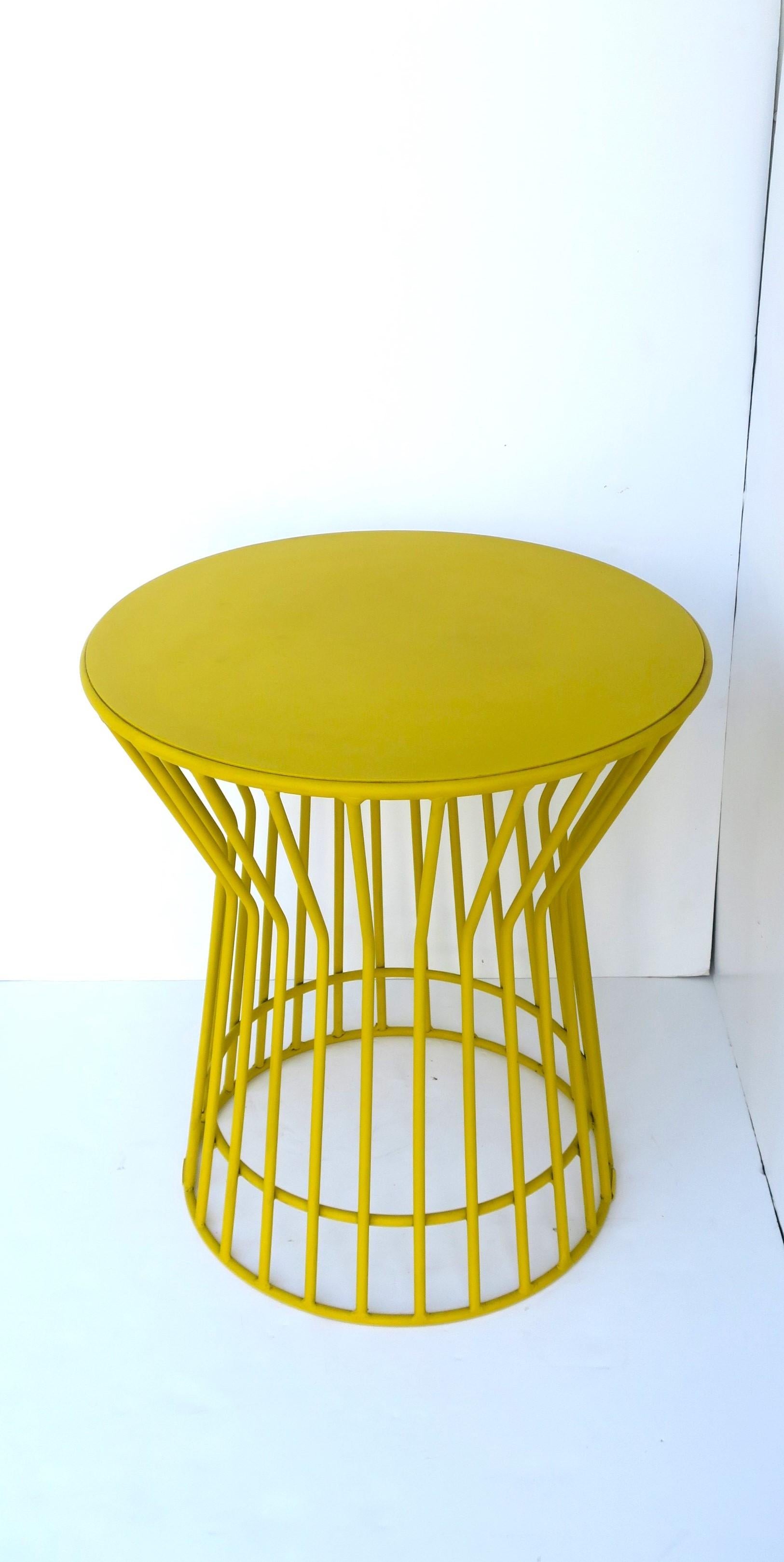 A round yellow powder-coated metal end or side table with hourglass design, in the Midcentury Modern or Postmodern design style, with a Warren Platner design influence. circa late-20th century to early 21st century. Dimensions: 20