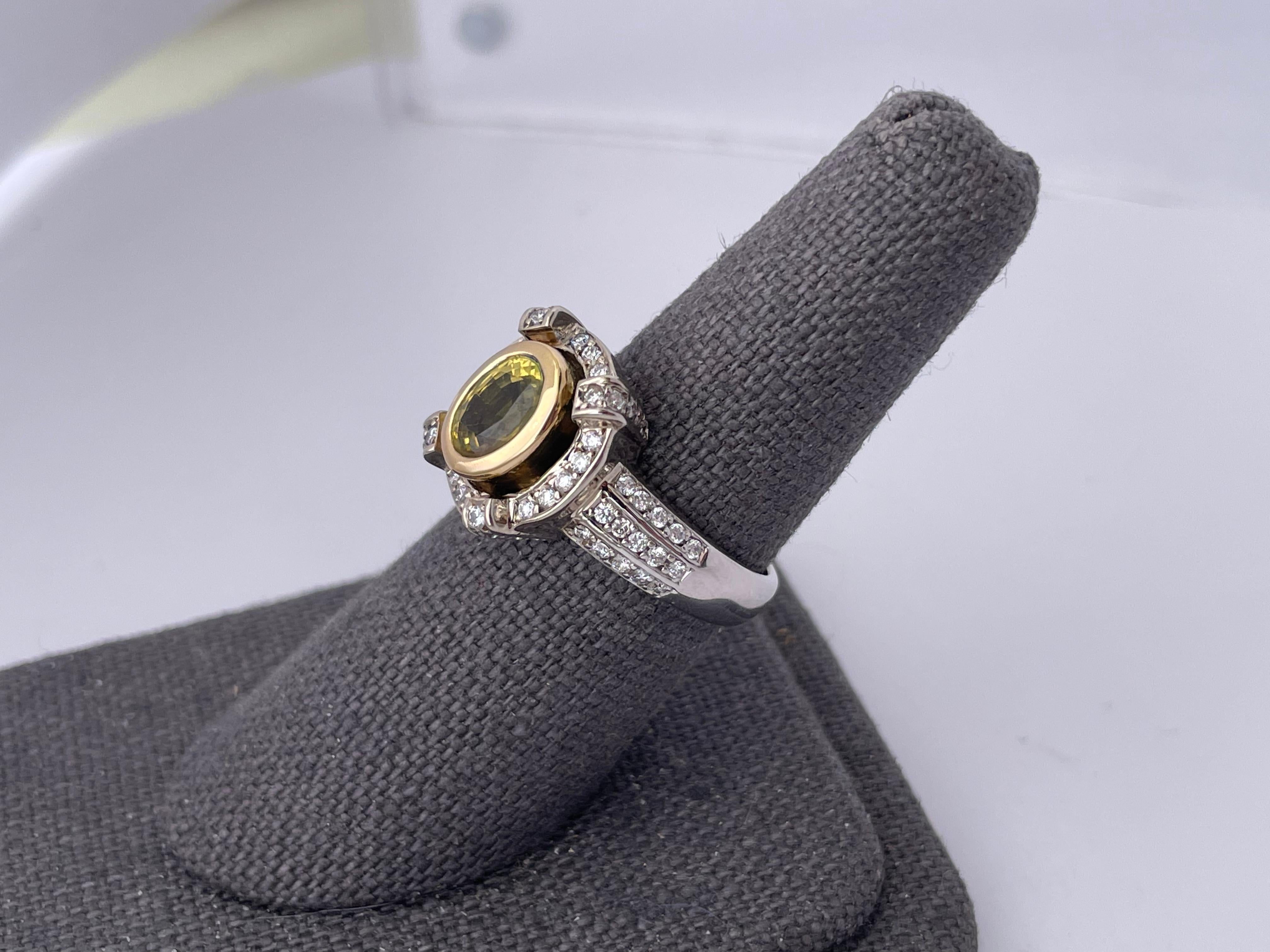 14kt White gold ring with three faux channel rows of prong set diamonds accompanied by a diamond halo with faux prongs prong set with round brilliant diamonds. The center Yellow sapphire is bezel set in yellow gold to enhance the yellow color of the