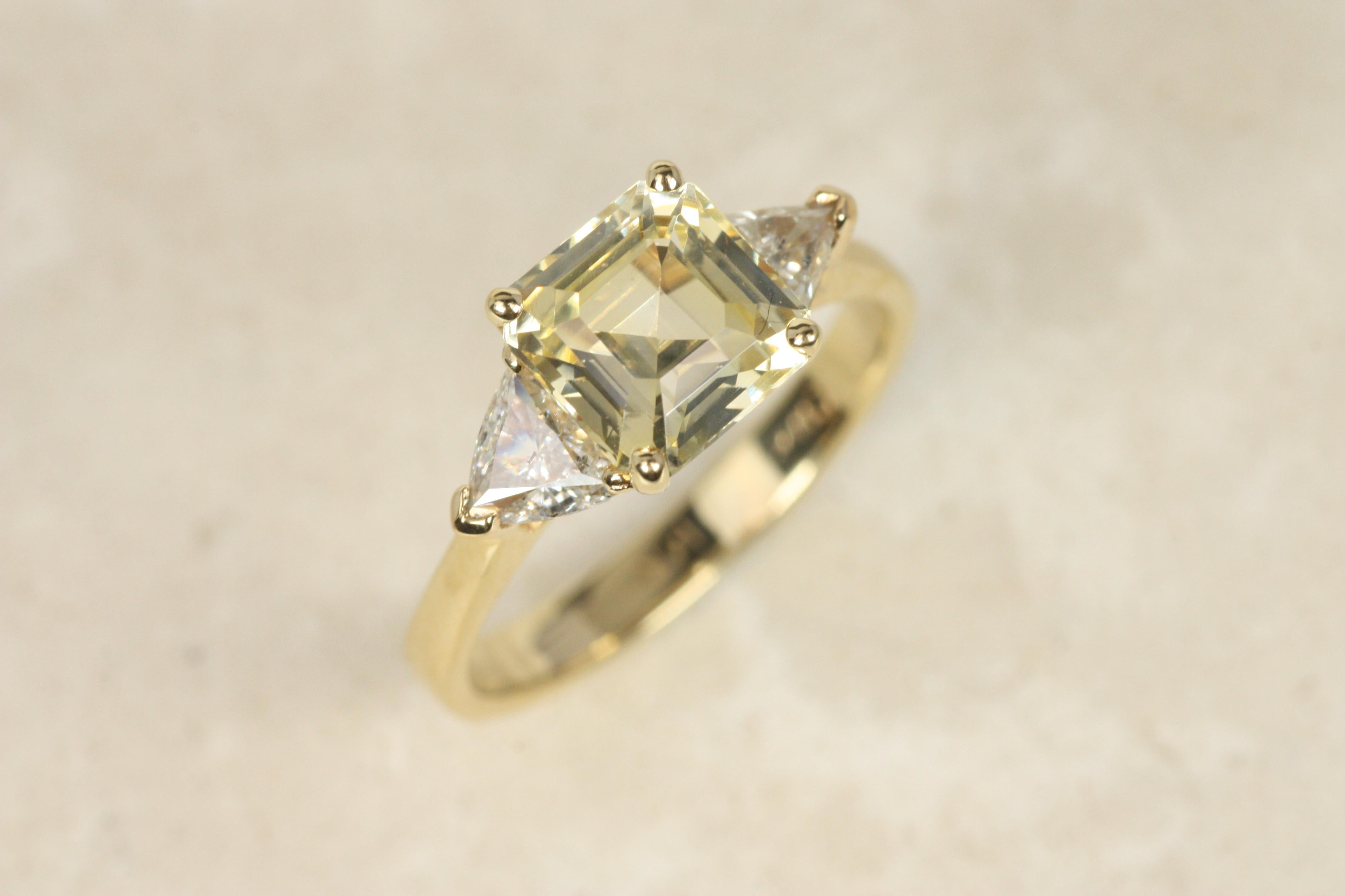 Pour celles qui recherchent une bague de fiançailles non traditionnelle ou une pièce colorée, cette bague à trois pierres en saphir jaune et diamant offre une beauté rayonnante. Le saphir jaune carré de 2,14ct, taillé en émeraude, est flanqué de