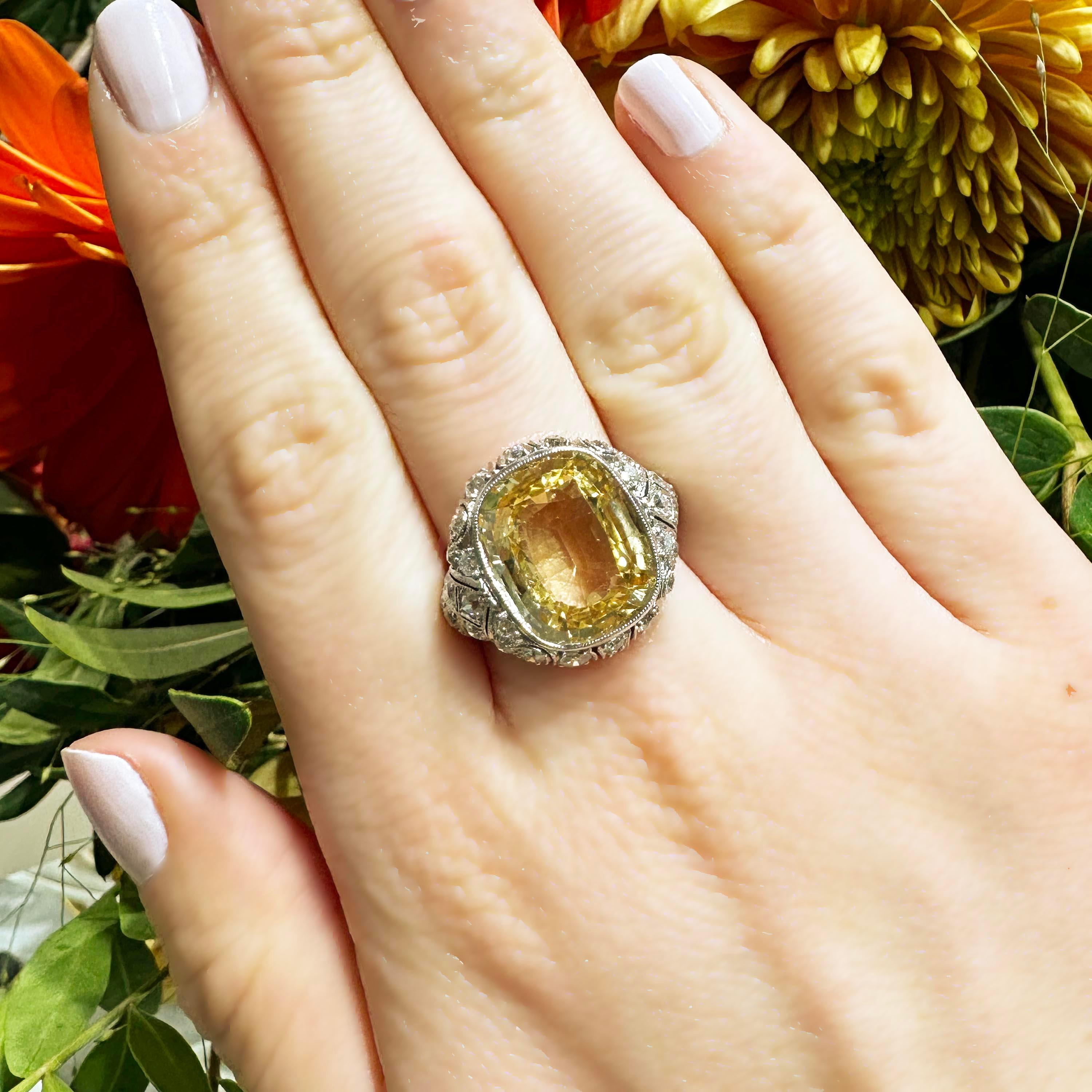 A yellow sapphire dress ring, set with a faceted, cushion shaped, mixed cut yellow sapphire, in a millegrain edged rub over setting, with a decorative old-cut diamond set surround and shoulders, with millegrain edges and openwork, mounted in