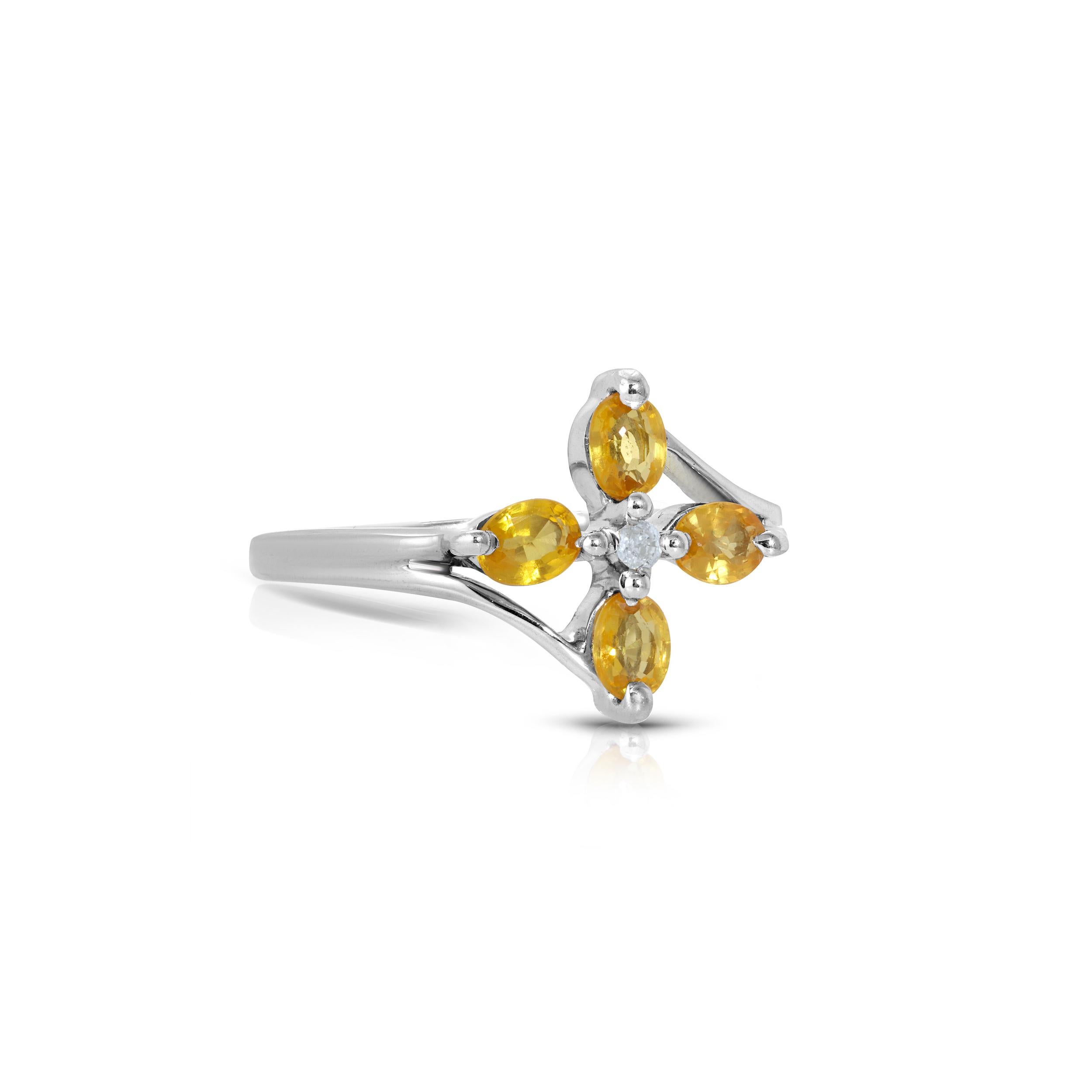A cocktail ring in a modern flower design featuring a mix of gemstones. This beautiful ring features Four oval cut yellow Sapphires with a total Carat weight of .92 set around a .03 Carat center Diamond. This ring is set in 18 Karat White Gold