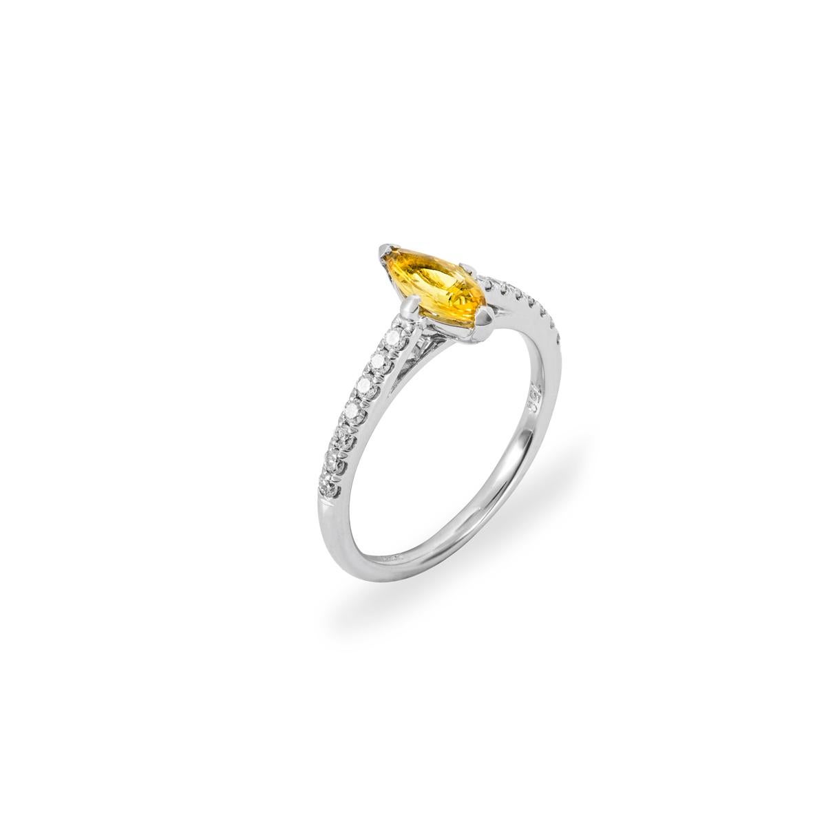 A charming yellow sapphire and diamond ring set in 18k white gold. The ring features a marquise cut vivid yellow sapphire set to the centre weighing 0.57ct. Accentuating the yellow sapphire are 14 round brilliant cut diamonds pave set to the