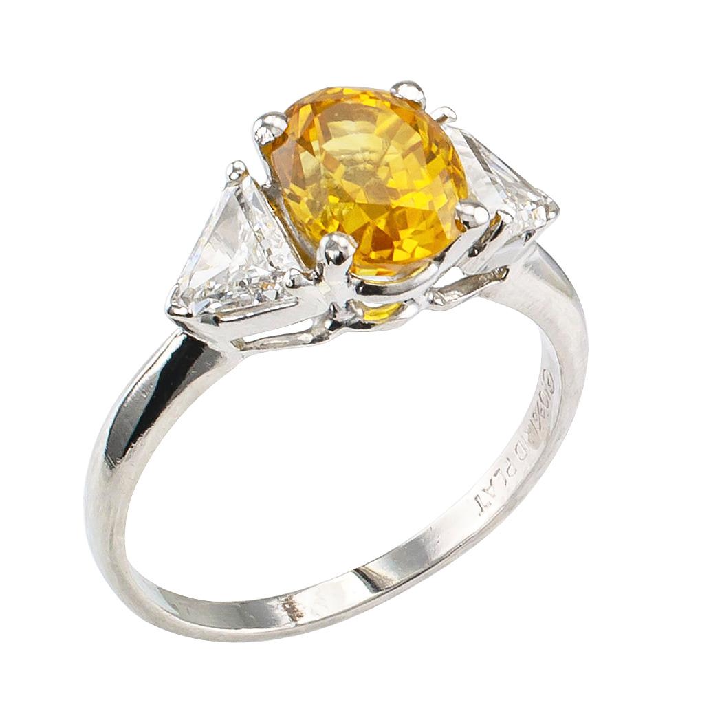 Yellow sapphire diamond and platinum three stone ring circa 1970. Centering upon an oval yellow sapphire weighing 2.06 carats between a pair of triangular diamonds totaling approximately 0.75 carat, approximately F – G color and VS clarity, mounted