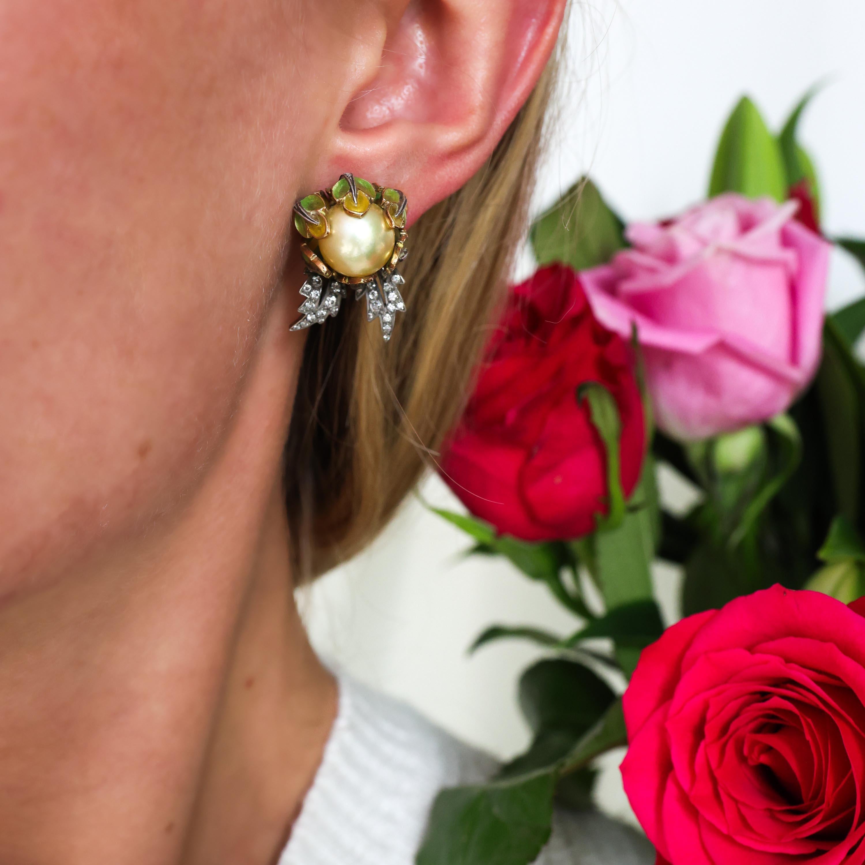 A pair of golden pearl, diamond and plique à jour enamel flower earrings, each designed as flower buds, set with a golden, South Sea pearl, surrounded by yellow to green plique à jour enamel petals, with openwork silver leaves, grain set with