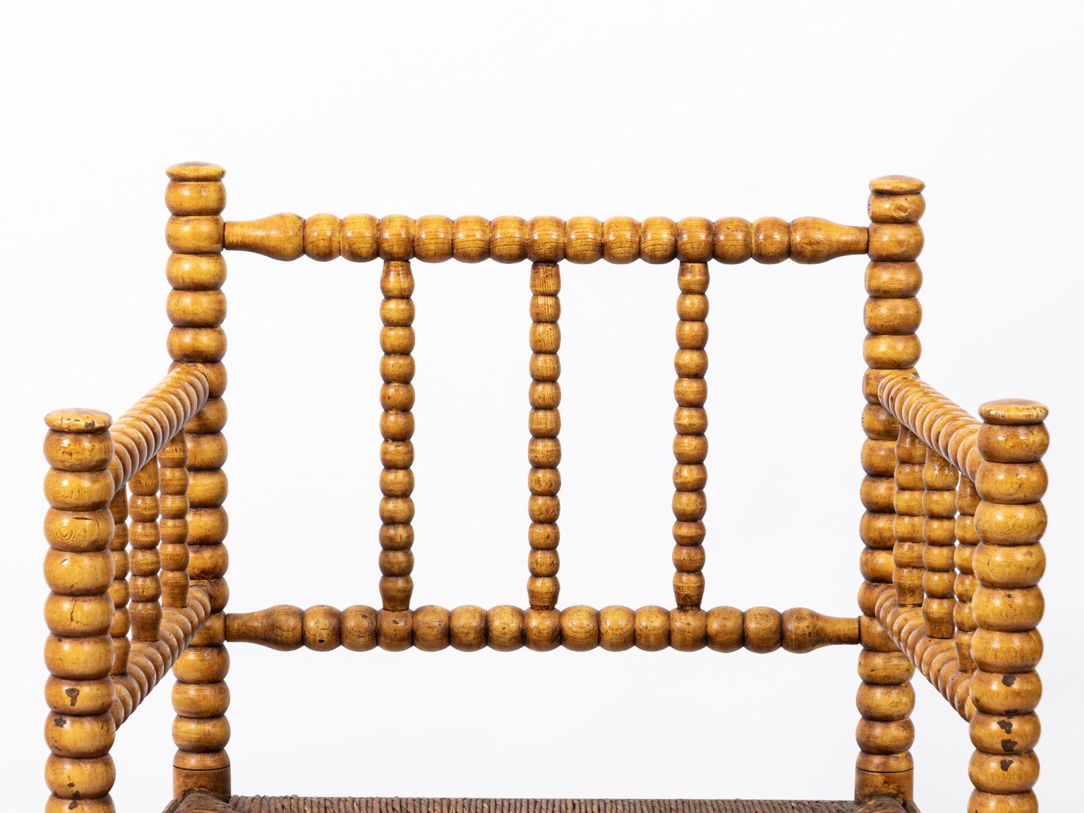 Yellow spool turned armchair with woven seating. Please note of wear consistent with age including minor scuffs due to daily use.