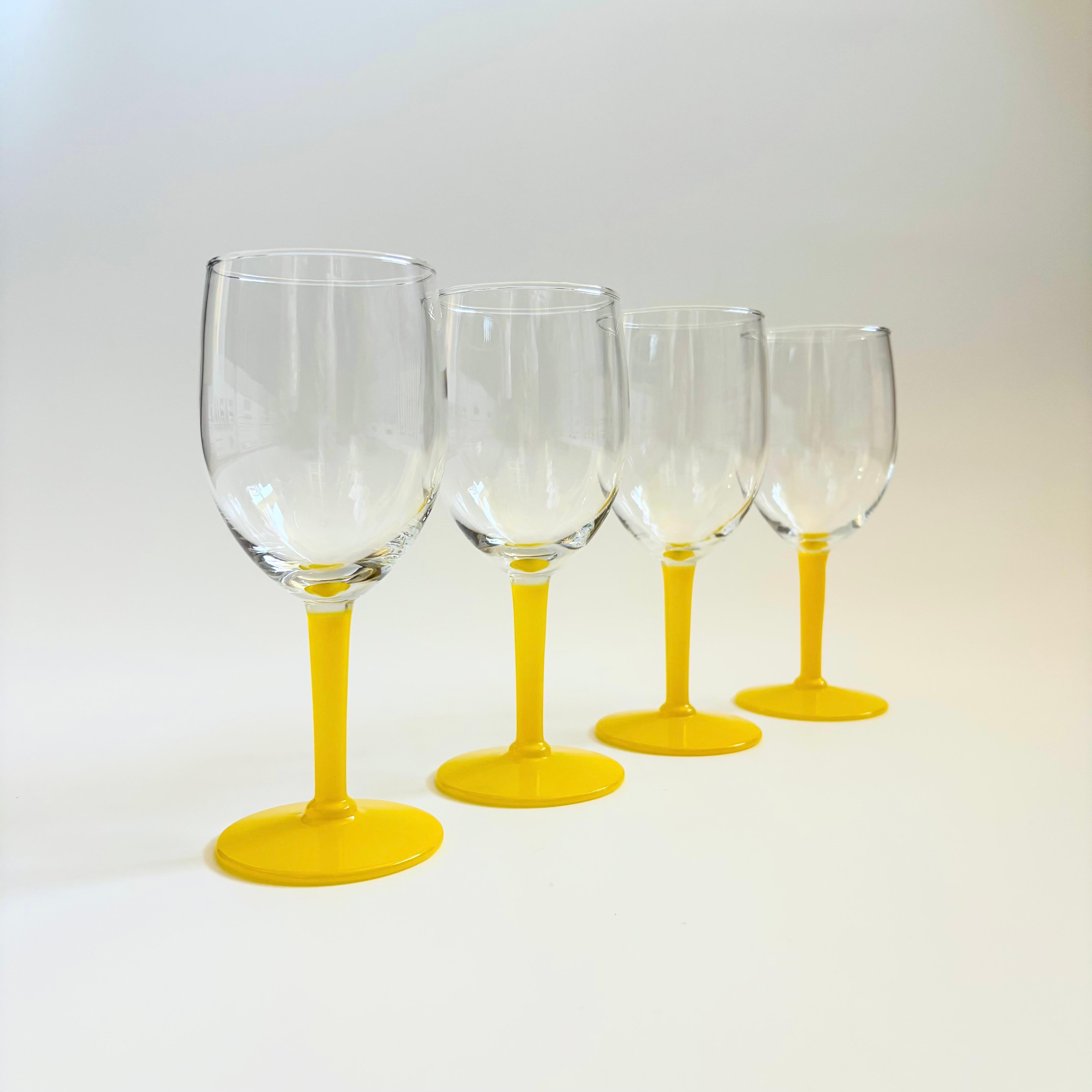 A lovely set of 4 vintage wine glasses, each with a clear top and vibrant yellow stem.

