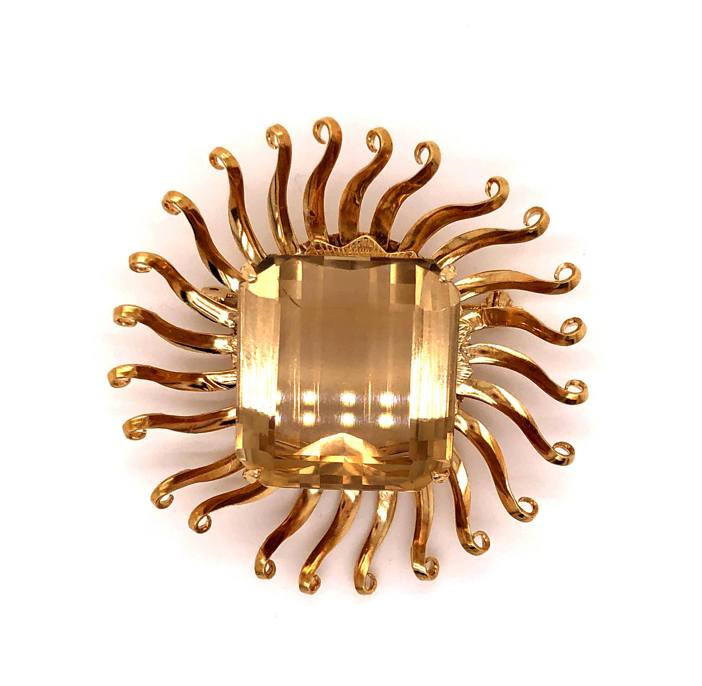 Three dimensional 18k yellow gold sun brooch featuring a centrally set faceted square shaped yellow topaz with gold rays of light bursting outwards.
Marked 18k.