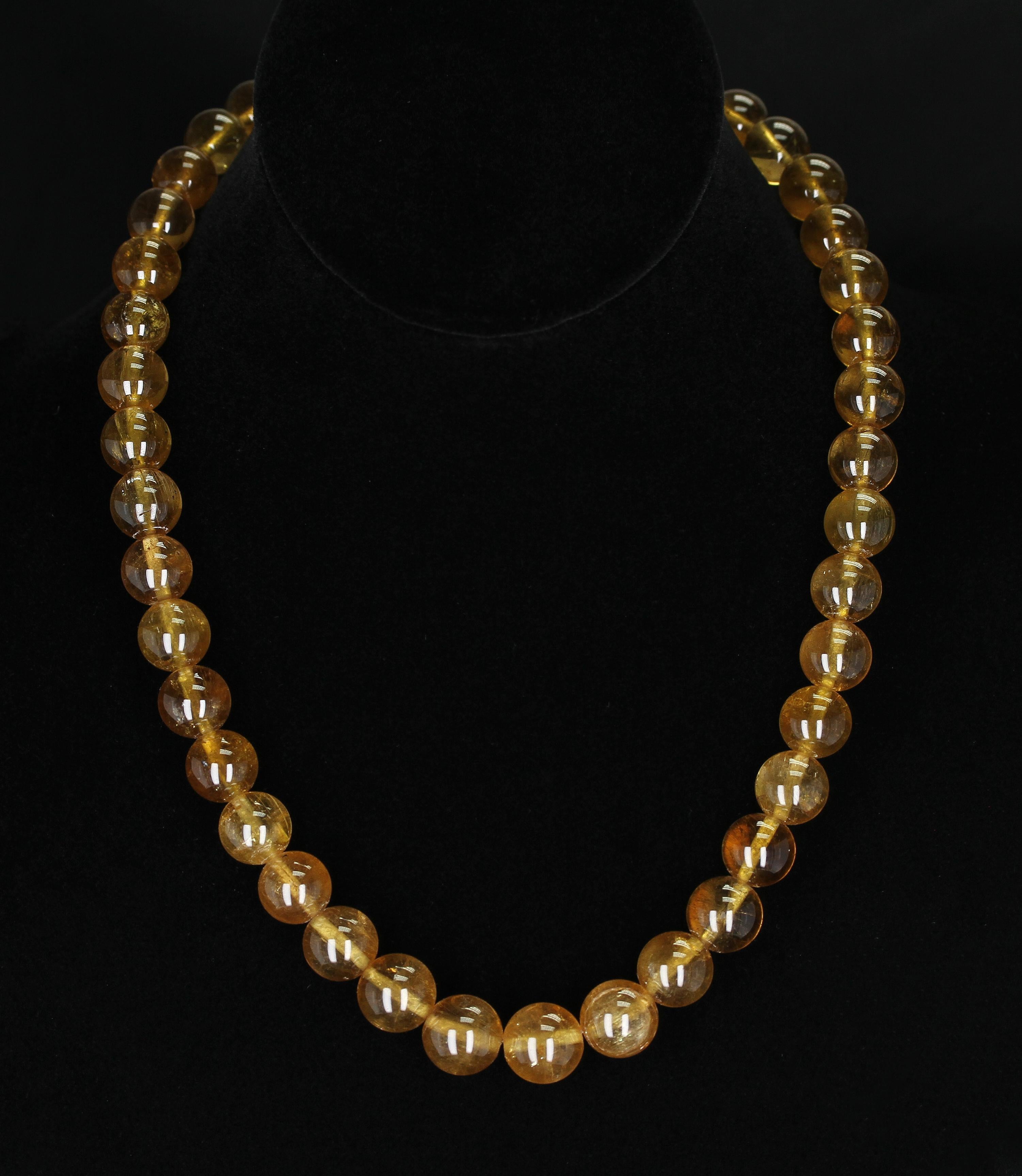 A unique bead necklace with spherical (round) beads of yellow tourmaline with good clarity and perfectly matched; accented with an oxidized gold clasp set with yellow sapphires. The tourmalines measure from 11 mm to 12.75 mm, with the total weight