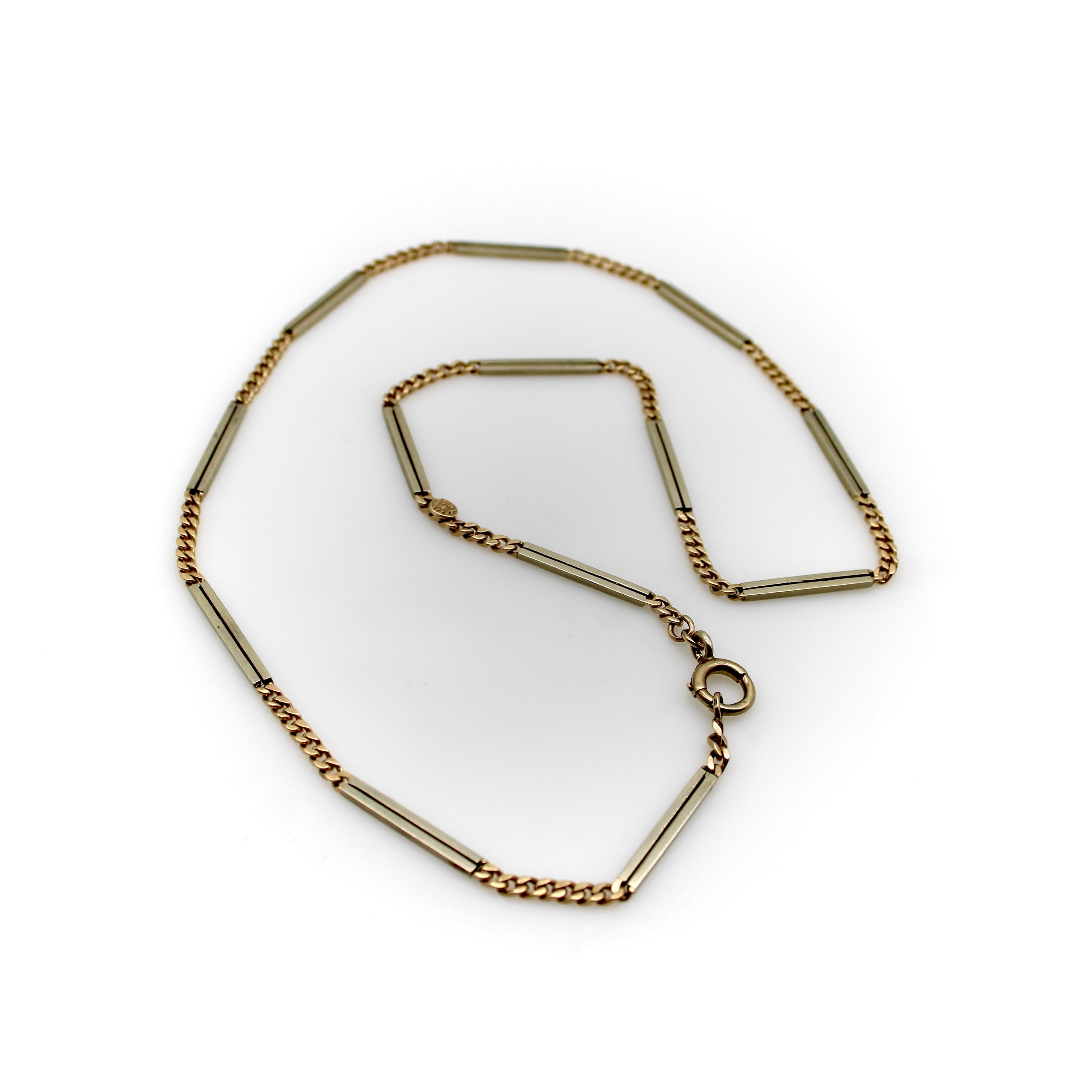 Alternating between links of white and yellow gold, this 14k Art Deco watch chain is bold and unique. The white gold sections of the chain consist of bisected bar links with narrow beams of open space down the center of the bars. On either end of