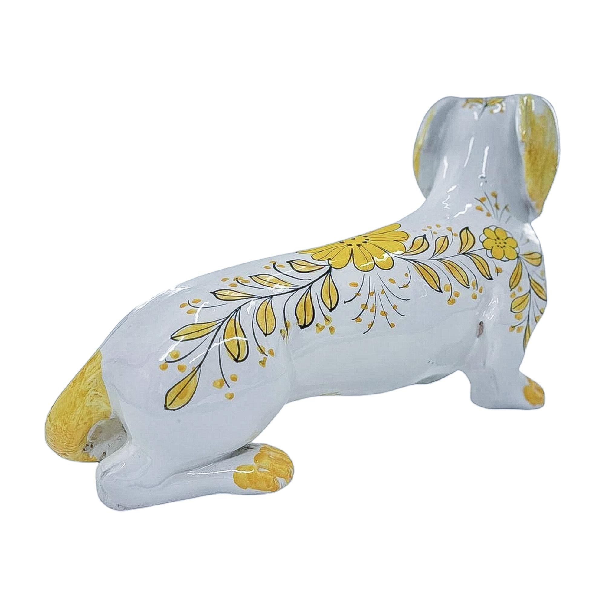 Delight in the graceful presence of this vintage Italian porcelain dachshund, hand-painted with delicate floral motifs in soft yellow tones. The serene blue eyes, golden-tipped paws, and finely detailed brushwork capture a timeless elegance that