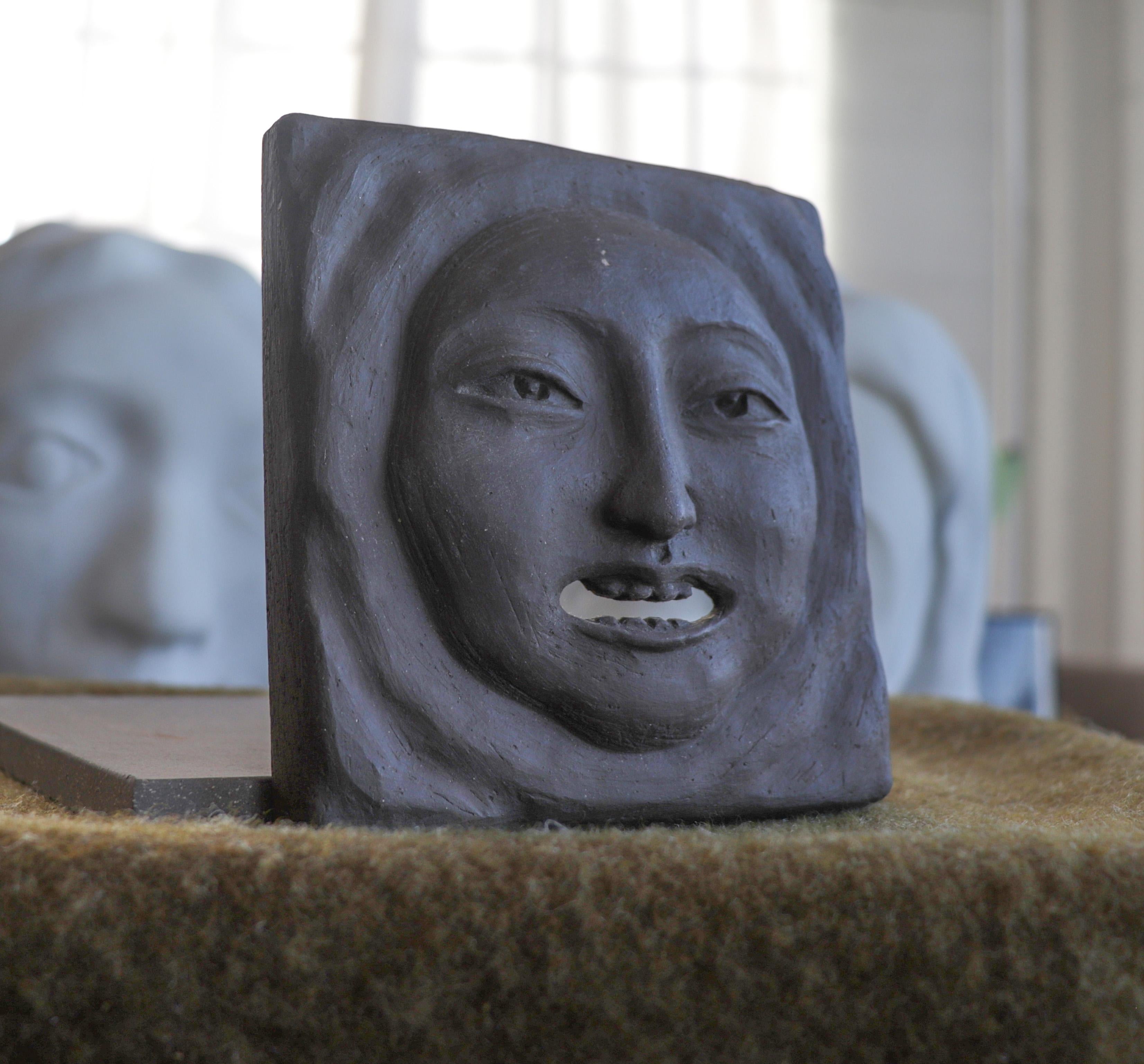 This grinning face tile is by Korean sculptor Yeon Koh Warner (b. 1967). Warner was born in Seoul, South Korea in 1967. She graduated from Seoul National University in 1990 with a degree in sculpture. In 1991 she moved to Rome to further pursue