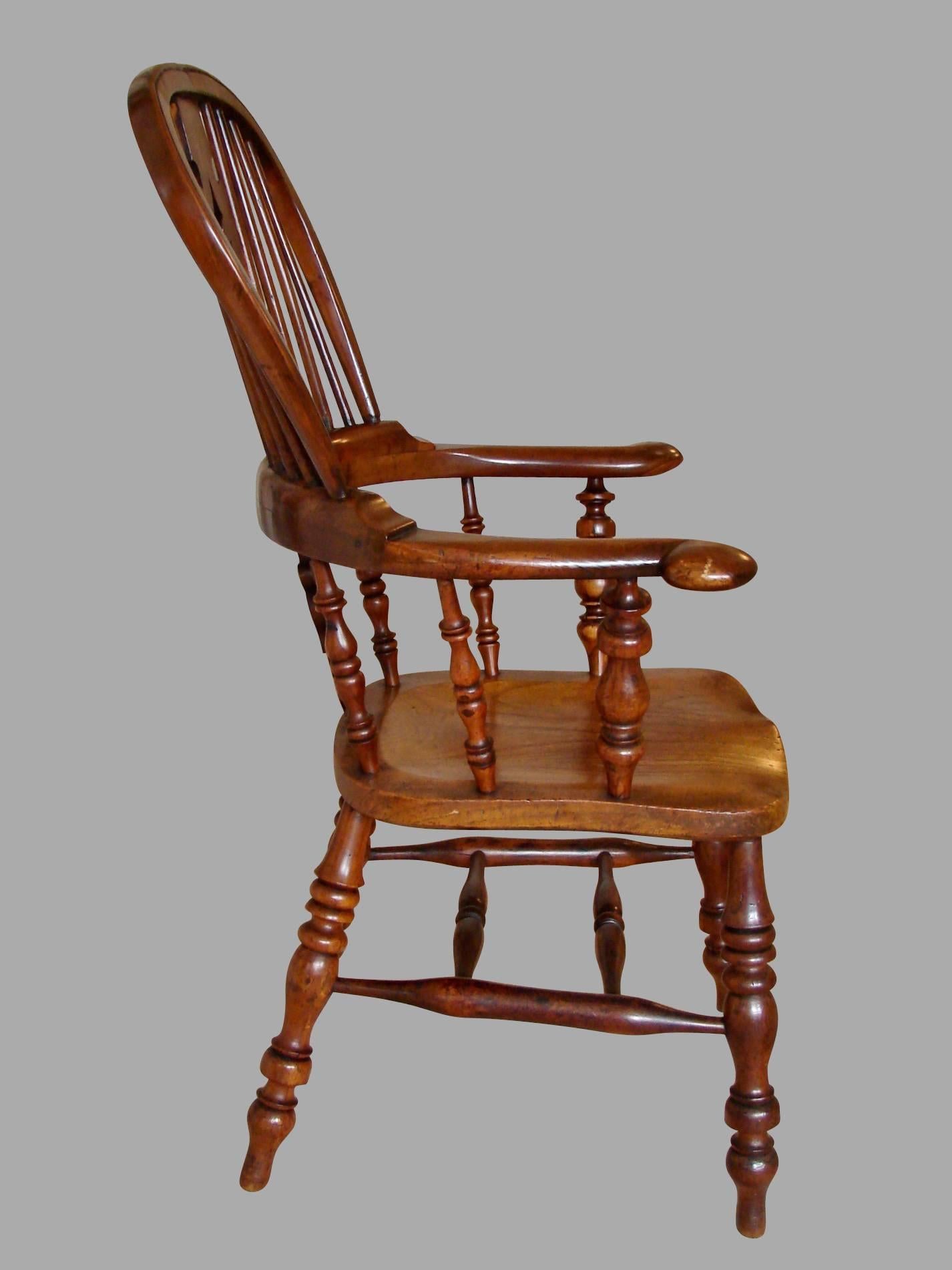 A good English yew wood broad arm high back Windsor chair with a Christmas tree splat, the hickory seat supported on well-turned legs joined by single stretcher, circa 1840-1860.