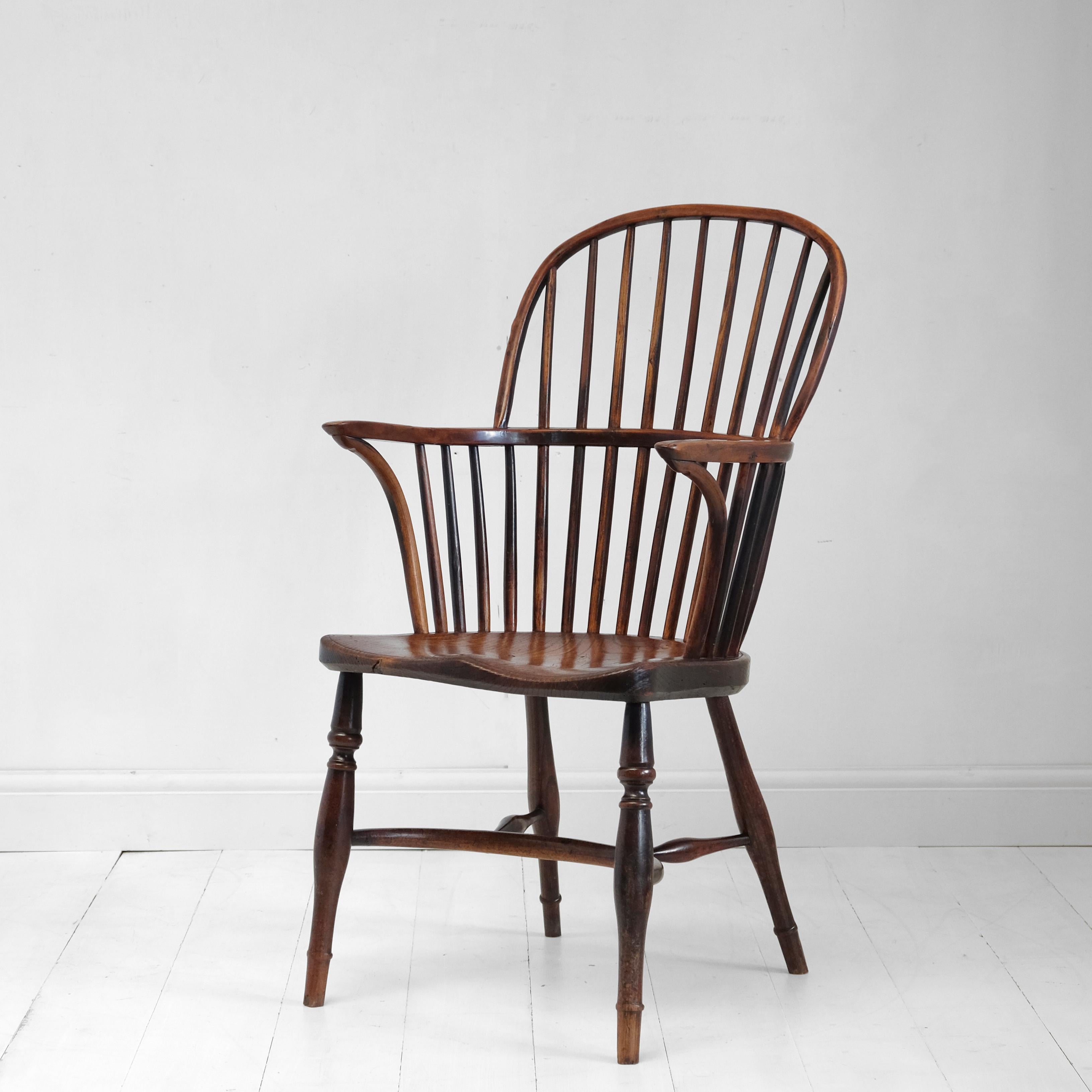 A good antique English Windsor chair in yew and ash with elm seat. Turned legs with crinoline stretcher, saddle-shaped seat with attractive grain pattern, yew arm and back hoop with simple stick back. The whole with a rich, warm color. Good solid