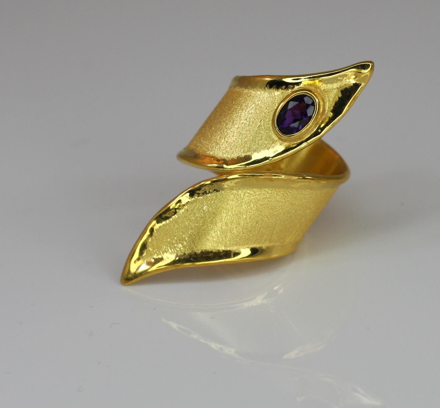 Yianni Creations presents a wide handmade artisan ring crafted from 18 Karat yellow gold. This asymmetric gorgeous ring features 0.45 Carat oval cut Amethyst.  The beautiful piece due to its opened design adjusts in size, meaning you can wear it on