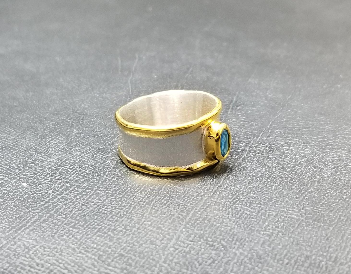 Men's and women's Yianni Creations Midas Collection fully handmade artisan band ring made from Fine silver plated with platinum and decorated with a thick overlay of 24 Karat yellow gold. This band features 0.57 Carat oval-shape London blue topaz.
