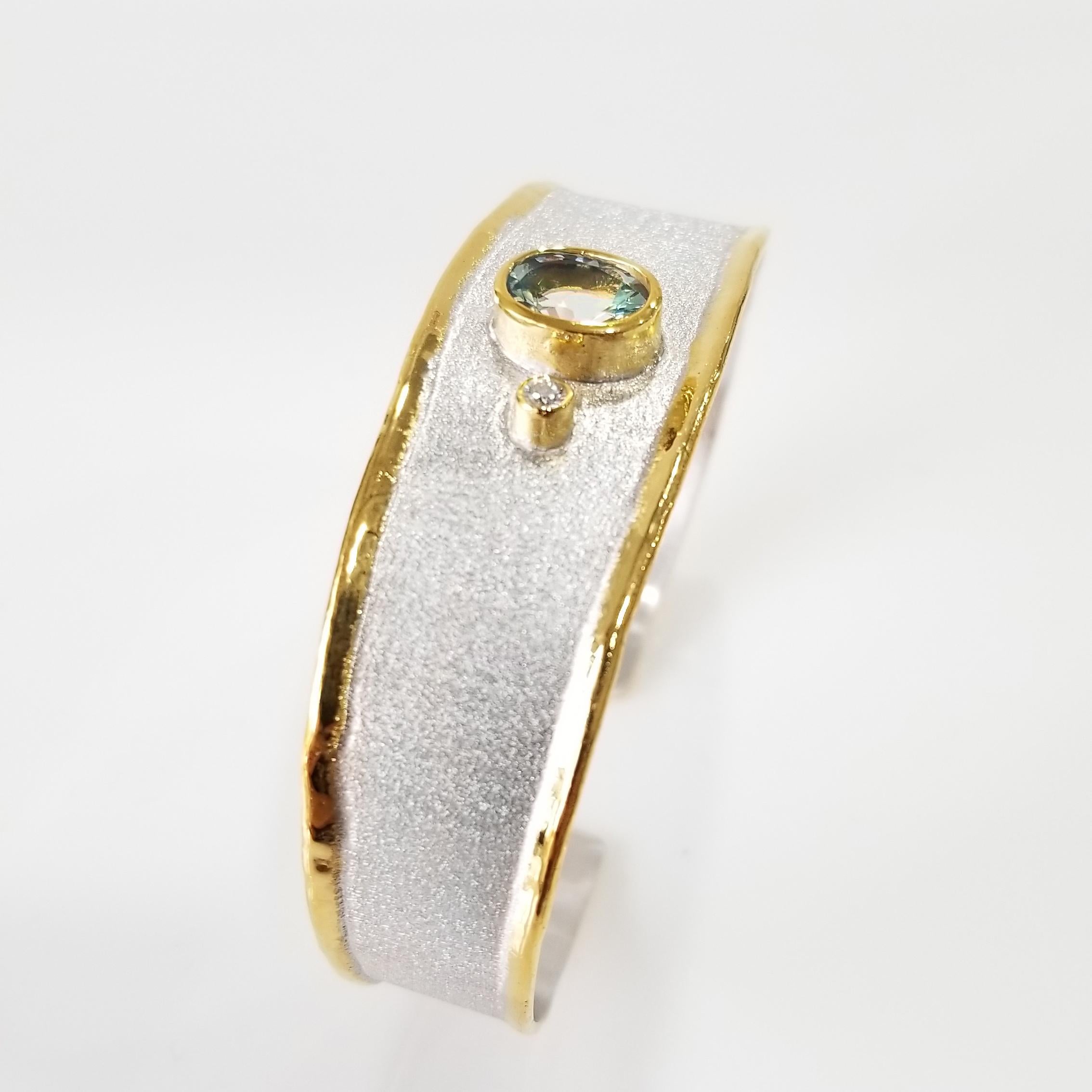 Presenting Yianni Creations bangle bracelet from Midas Collection all handcrafted from fine silver 950 purity and plated with palladium to resist the elements. This artisan bracelet features 1.10 Carat oval shape aquamarine accompanied by 0.03 Carat
