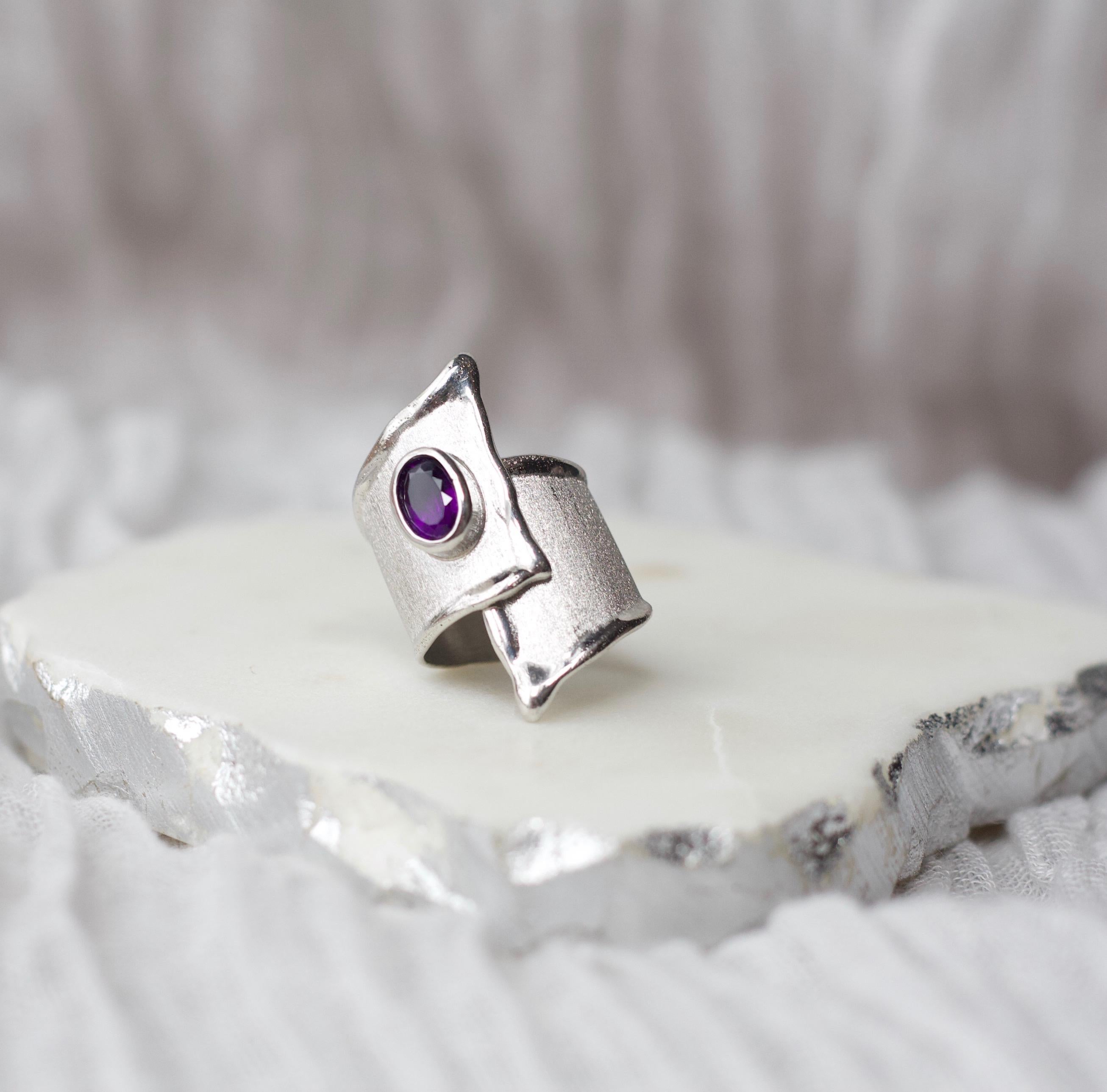 This is Yianni Creations adjustable ring from Ammos Collection all handcrafted from fine silver 950 purity and plated with palladium to resist the elements. The ring features 1.25-carat oval cut amethyst complemented by unique techniques of