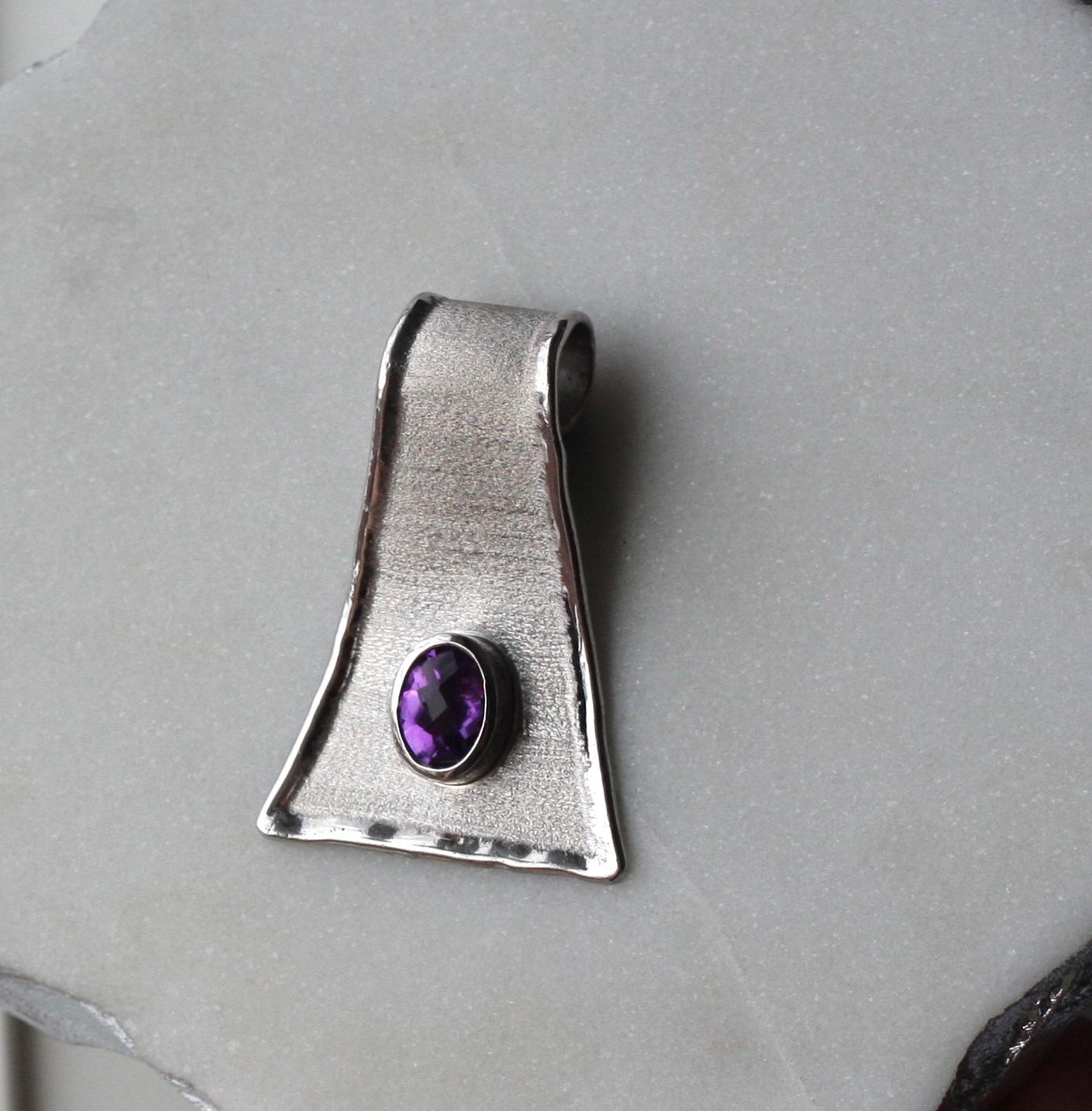 This is Yianni Creations fine silver 950 purity plated with palladium pendant from Ammos Collection crafted in Greece and featuring 1.25 Carat oval cut amethyst. The unique look of this enhancer is created by combining two techniques of