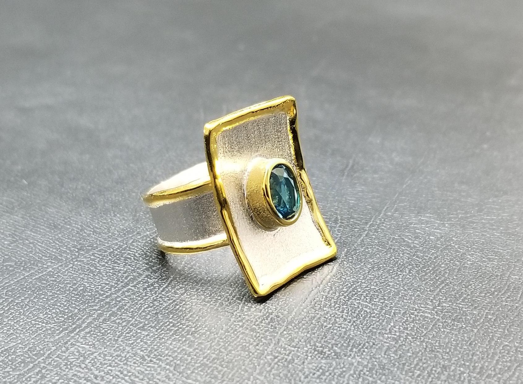 Der Ring aus der Midas-Kollektion von Yianni Creations ist ein vollständig handgefertigter Ring aus Feinsilber, das mit Palladium überzogen ist, und mit einer Auflage aus 24 Karat Gelbgold. Der Ring ist mit einem 1,25 Karat Londoner Blautopas