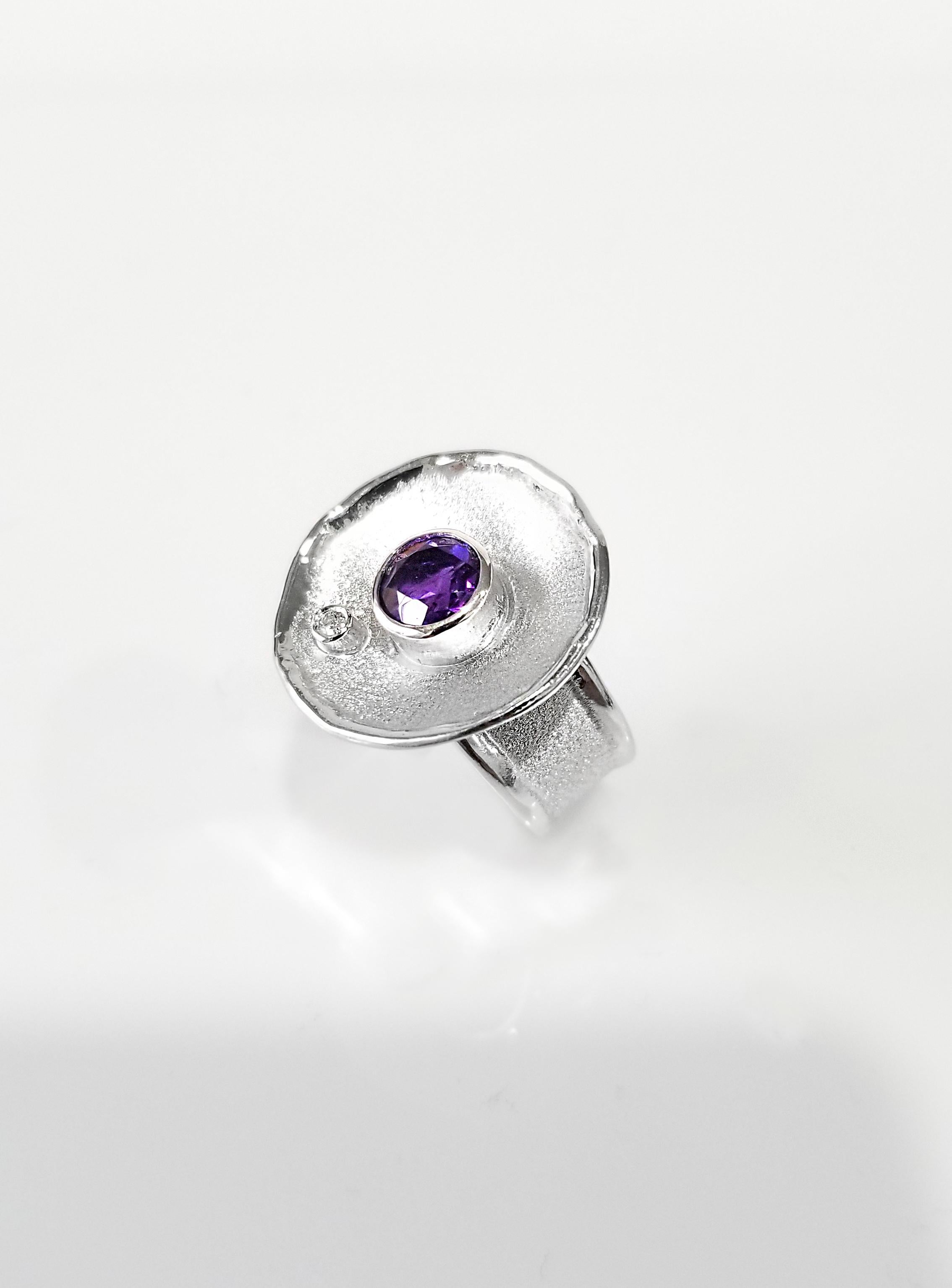 Presenting Yianni Creations Ammos Collection handmade artisan ring from fine silver 950 purity plated with palladium to resist against elements. This round ring features 1.30 carat round cut Amethyst accompanied by a 0.03-carat brilliant-cut white