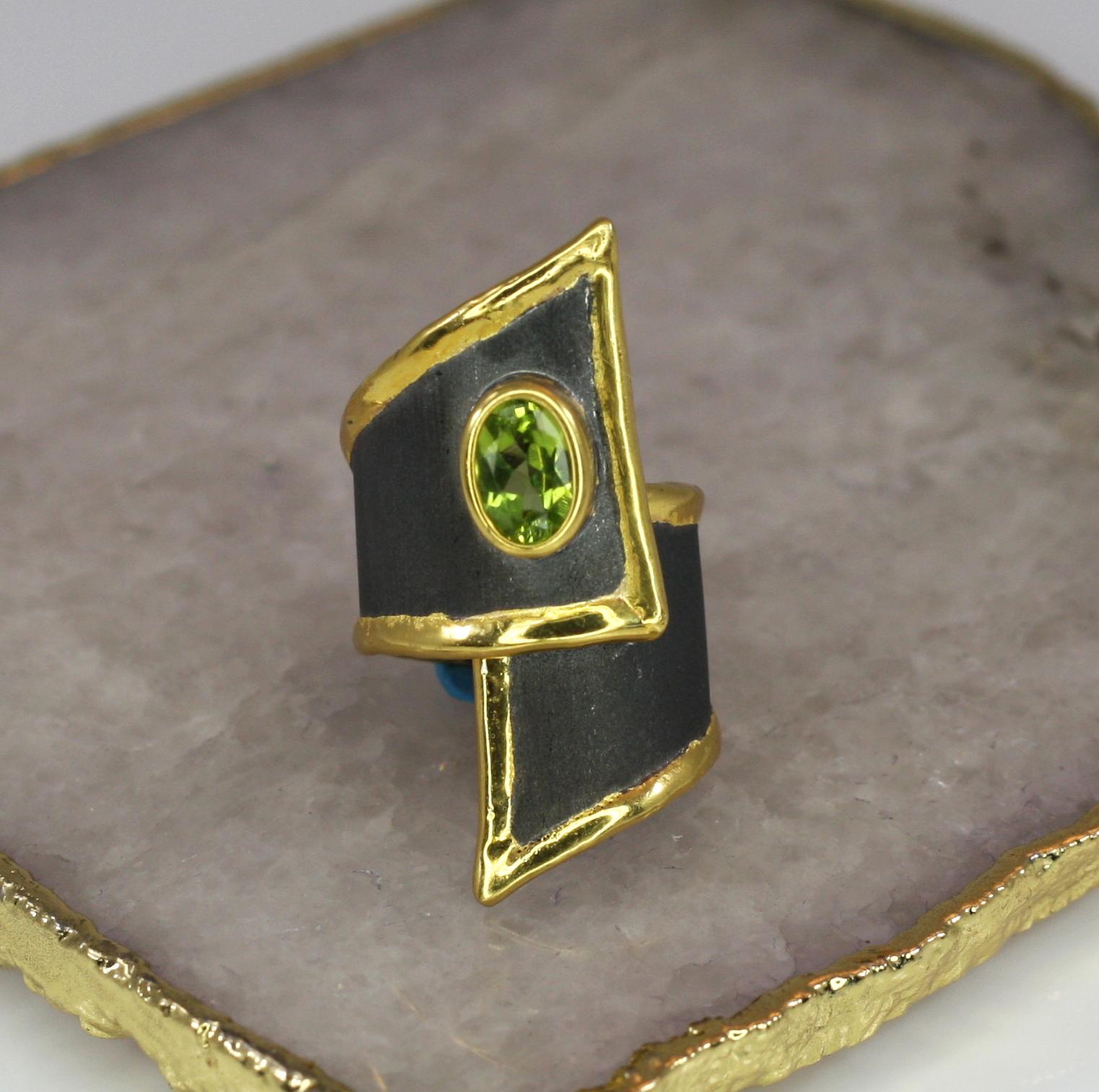 Yianni Creations präsentiert exklusiv die neue Eclyps-Kollektion. Dies ist ein handgefertigter Ring aus Feinsilber 950 Reinheit mit schwarzem Rhodium und reinem Gold überzogen. Dieser breite asymmetrische Ring zeigt einen Peridot mit 1,35 Karat im
