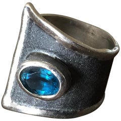 Yianni Creations Anello a fascia larga in argento fine e rodio nero con topazio blu