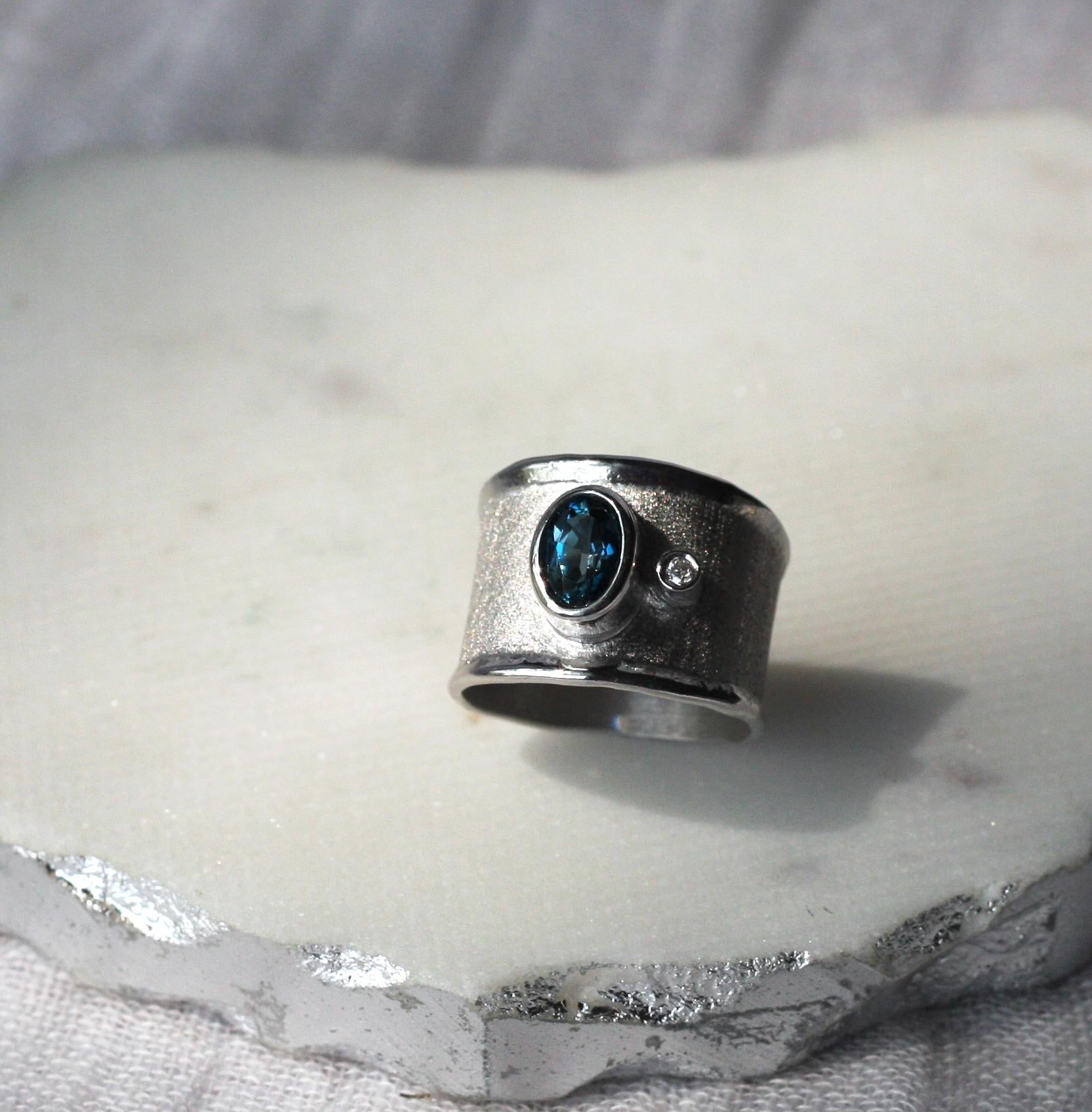 This is Yianni Creations ring from Ammos Collection 100% handmade from fine silver and plated with palladium to resist tarnish. This ring is featuring 1.60 Carat Oval Cut London Blue Topaz accompanied by 0.03 Carat Brilliant-cut White Diamond and