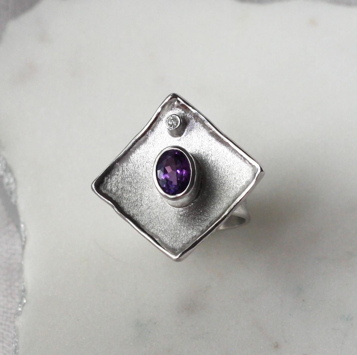 This Yianni Creations handmade band ring from Ammos Collection is 100% handcrafted in Greece from Fine silver 950 purity and plated with palladium to resist the elements. The stunning ring features a 1.25 Carat Amethyst oval cut complimented by a