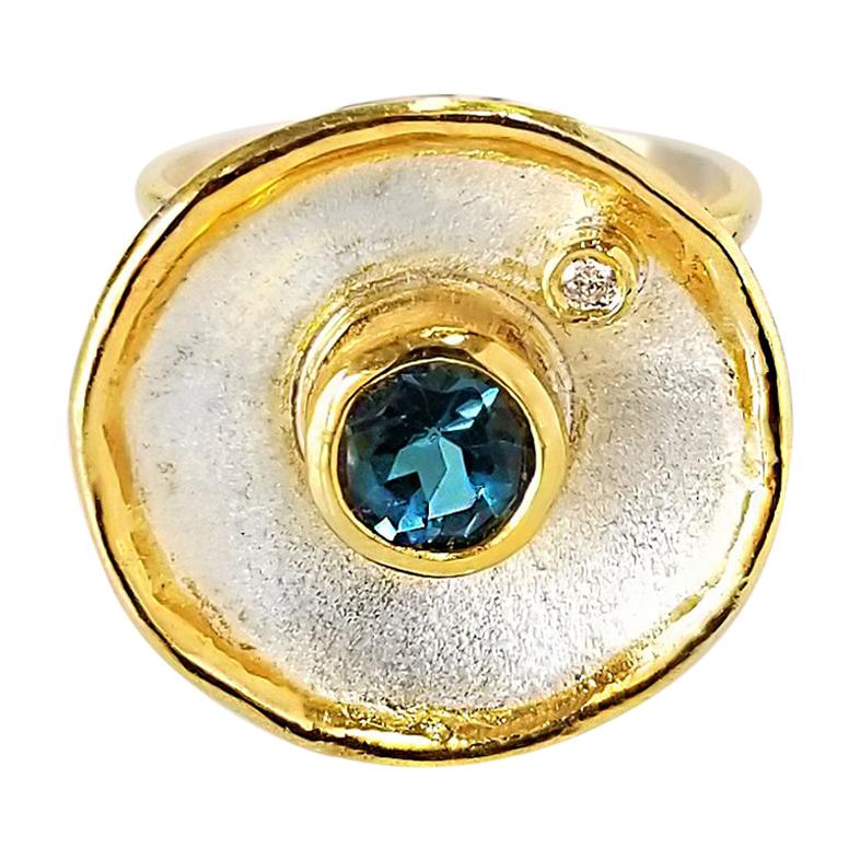 Yianni Creations Fine Silver with an overlay of 24 Karat Yellow Gold 3.5+ microns, features a 1.55 Carat London Blue Topaz accompanied by a brilliant-cut Diamond weight of 0.03 Carat. This gorgeous band ring is made with a unique technique of